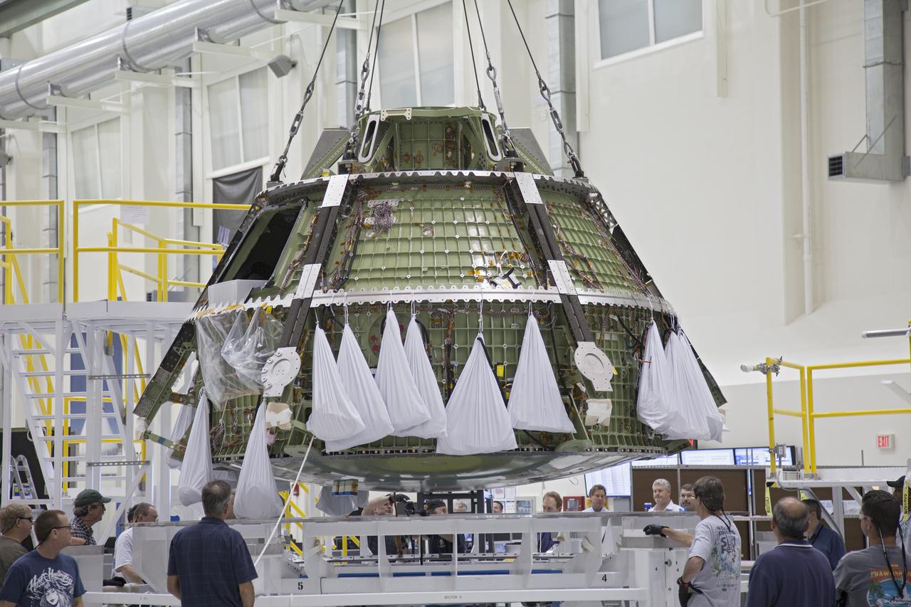 CAPE CANAVERAL, Fla. -- Inside the Operations and Checkout Building high bay at NASA’s Kennedy Space Center in Florida, workers monitor the progress as a crane begins to lift the Orion crew module from its processing stand and transfer it to a dolly. Orion is being prepared for Exploration Flight Test 1, or EFT-1. Orion is the exploration spacecraft designed to carry crews to space beyond low Earth orbit. It will provide emergency abort capability, sustain the crew during the space travel and provide safe re-entry from deep space return velocities. Orion’s first unpiloted test flight is scheduled to launch in 2014 atop a United Launch Alliance Delta IV heavy rocket. A second uncrewed flight test is scheduled for 2017 on the Space Launch System rocket. For more information, visit http:__www.nasa.gov_orion. Photo credit: NASA_Frankie Martin