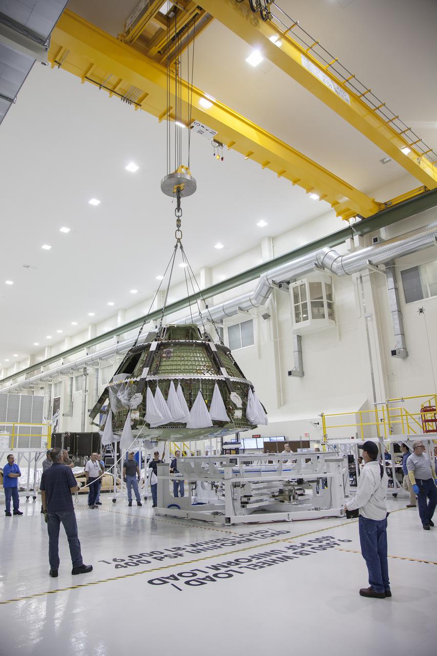 CAPE CANAVERAL, Fla. -- Inside the Operations and Checkout Building high bay at NASA’s Kennedy Space Center in Florida, workers monitor the progress as a crane lifts the Orion crew module from its processing stand for transfer to a dolly. Orion is being prepared for Exploration Flight Test 1, or EFT-1. Orion is the exploration spacecraft designed to carry crews to space beyond low Earth orbit. It will provide emergency abort capability, sustain the crew during the space travel and provide safe re-entry from deep space return velocities. Orion’s first unpiloted test flight is scheduled to launch in 2014 atop a United Launch Alliance Delta IV heavy rocket. A second uncrewed flight test is scheduled for 2017 on the Space Launch System rocket. For more information, visit http:__www.nasa.gov_orion. Photo credit: NASA_Frankie Martin