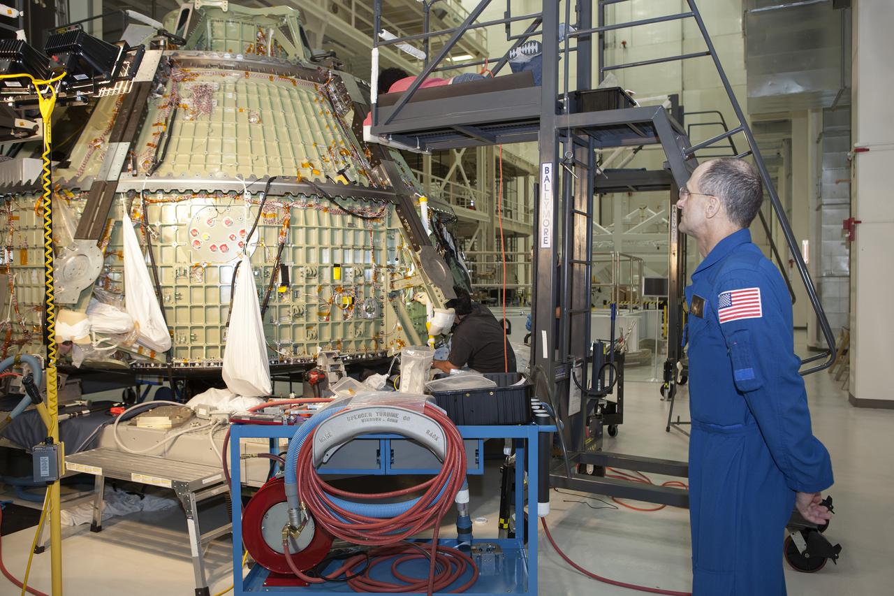 CAPE CANAVERAL, Fla. – Inside the Operations and Checkout Building high bay at NASA’s Kennedy Space Center in Florida, astronaut Don Pettit watches as technicians work on the Orion crew module. Orion is being prepared for Exploration Flight Test 1, or EFT-1. Orion is the exploration spacecraft designed to carry crews to space beyond low Earth orbit. It will provide emergency abort capability, sustain the crew during the space travel and provide safe re-entry from deep space return velocities. Orion’s first unpiloted test flight is scheduled to launch in 2014 atop a United Launch Alliance Delta IV heavy rocket. A second uncrewed flight test is scheduled for 2017 on the Space Launch System rocket. For more information, visit http:__www.nasa.gov_orion. Photo credit: NASA_Dimitri Gerondidakis