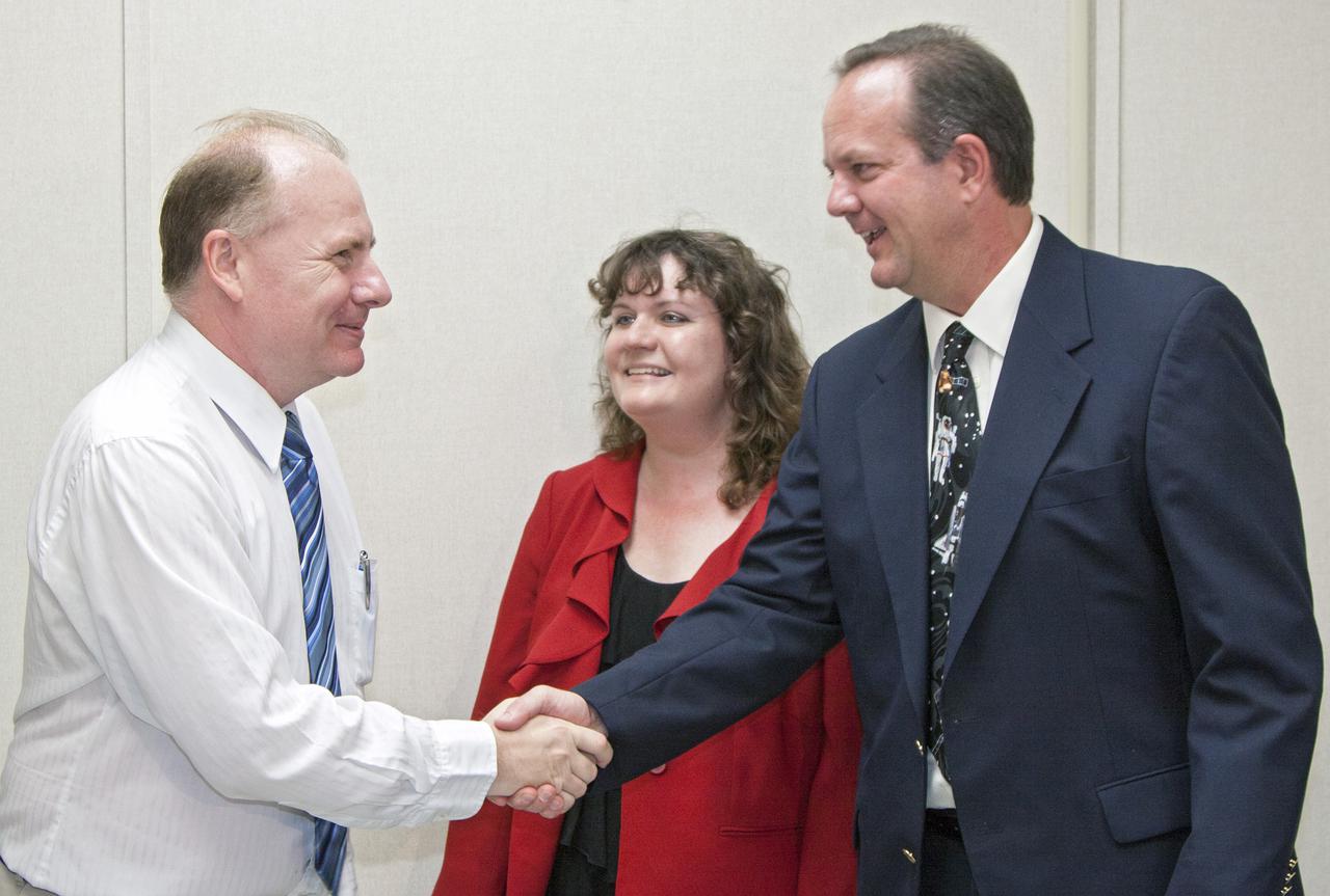 CAPE CANAVERAL, Fla. -- Inside the Space Station Processing Facility, or SSPF, at NASA’s Kennedy Space Center in Florida, Tom Engler, far right, deputy director of Kennedy’s Center Planning and Development Directorate, or CPDD, and Amy Houts-Gilfriche, a partnership development manager in CPDD, greet new partner Donald Platt with Micro Aerospace Solutions of Melbourne, Fla., during an official welcome ceremony, April 1.  NASA signed an agreement with Micro Aerospace Solutions on March 22 for use of an offline hardware processing laboratory and office space at the processing facility. Photo credit: NASA_Kim Shiflett