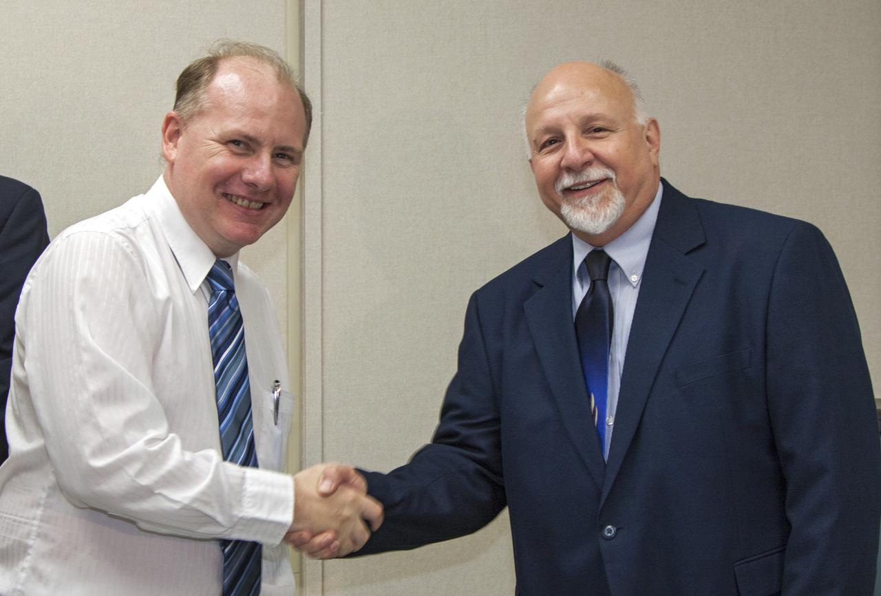CAPE CANAVERAL, Fla. -- Inside the Space Station Processing Facility, or SSPF, at NASA’s Kennedy Space Center in Florida, Cliff Hausmann, a technical integration manager in the Center Planning and Development Directorate, greets new partner Donald Platt with Micro Aerospace Solutions of Melbourne, Fla., during an official welcome ceremony, April 1.  NASA signed an agreement with Micro Aerospace Solutions on March 22 for use of an offline hardware processing laboratory and office space at the processing facility. Photo credit: NASA_Kim Shiflett