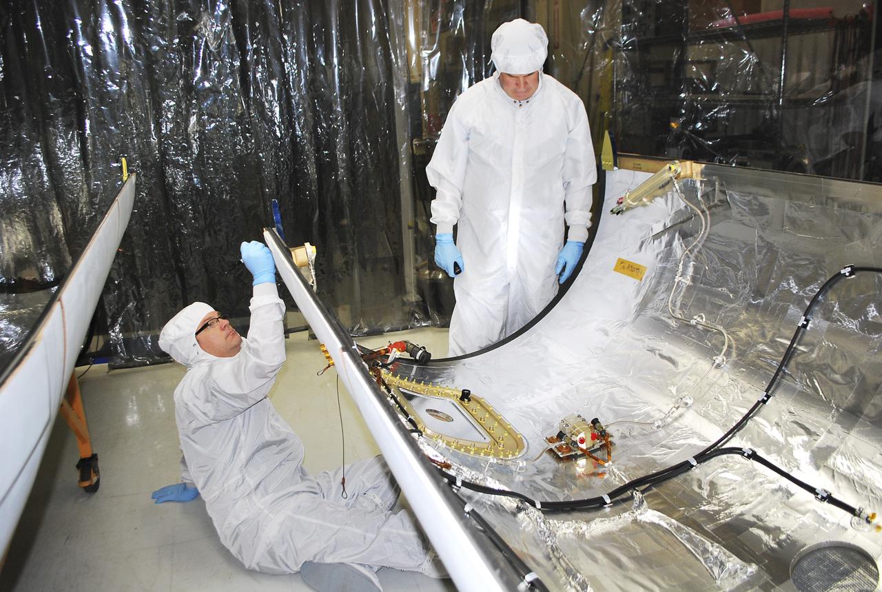 VANDENBERG AIR FORCE BASE, Calif. -- Technicians inside Building 1555 conduct inspection, cleaning and electrical testing on half of a payload fairing for the Orbital Sciences Corp. Pegasus XL rocket that will launch the Interface Region Imaging Spectrograph, or IRIS, spacecraft. The fairing will be fitted to the nose of the Pegasus to protect the spacecraft from atmospheric heating and stress during launch.    IRIS will open a new window of discovery by tracing the flow of energy and plasma through the chromospheres and transition region into the sun’s corona using spectrometry and imaging. IRIS fills a crucial gap in our ability to advance studies of the sun-to-Earth connection by tracing the flow of energy and plasma through the foundation of the corona and the region around the sun known as the heliosphere.  Photo credit: VAFB_Randy Beaudoin