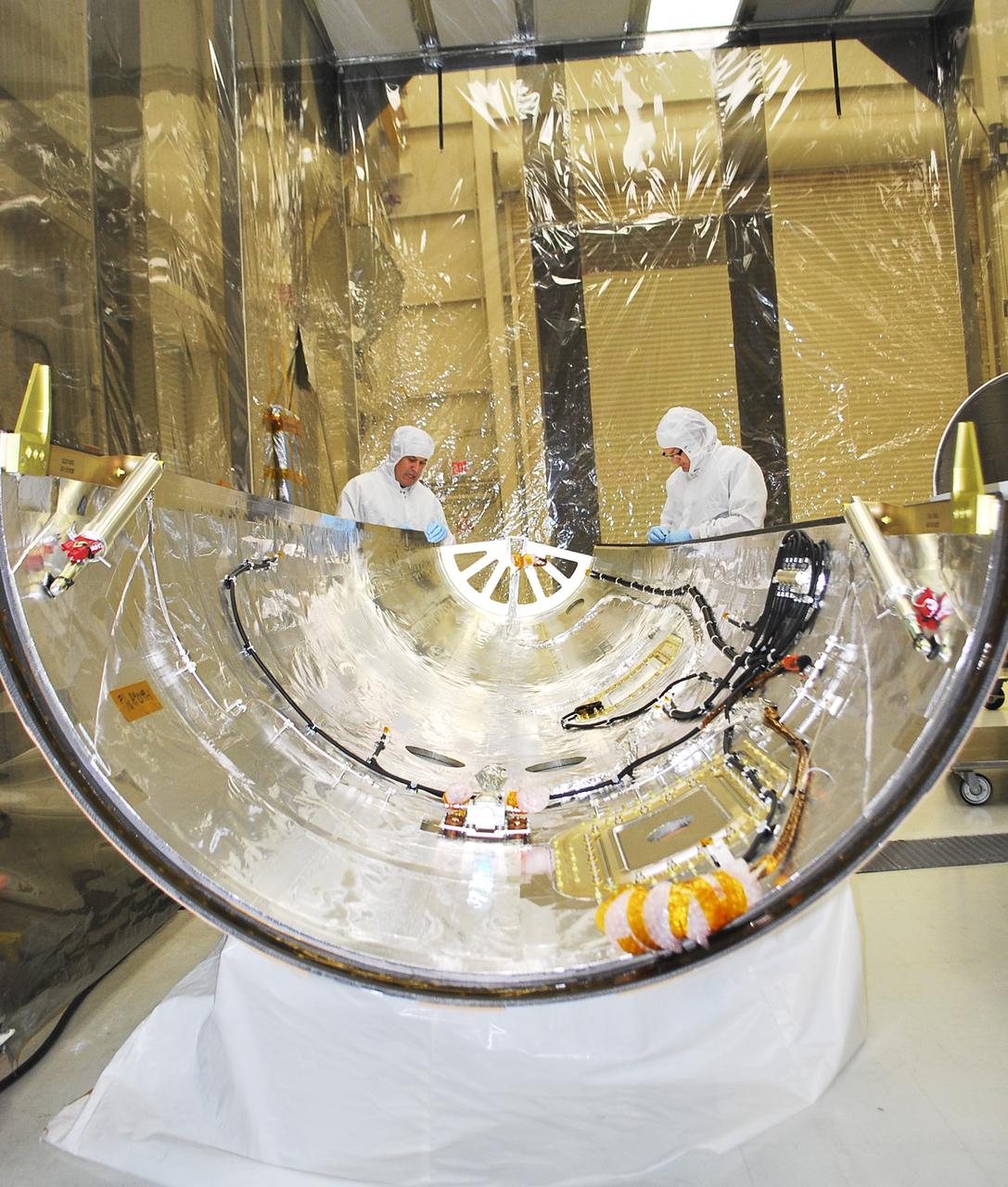 VANDENBERG AIR FORCE BASE, Calif. -- Technicians inside Building 1555 conduct inspection, cleaning and electrical testing on half of a payload fairing for the Orbital Sciences Corp. Pegasus XL rocket that will launch the Interface Region Imaging Spectrograph, or IRIS, spacecraft. The fairing will be fitted to the nose of the Pegasus to protect the spacecraft from atmospheric heating and stress during launch.    IRIS will open a new window of discovery by tracing the flow of energy and plasma through the chromospheres and transition region into the sun’s corona using spectrometry and imaging. IRIS fills a crucial gap in our ability to advance studies of the sun-to-Earth connection by tracing the flow of energy and plasma through the foundation of the corona and the region around the sun known as the heliosphere.  Photo credit: VAFB_Randy Beaudoin