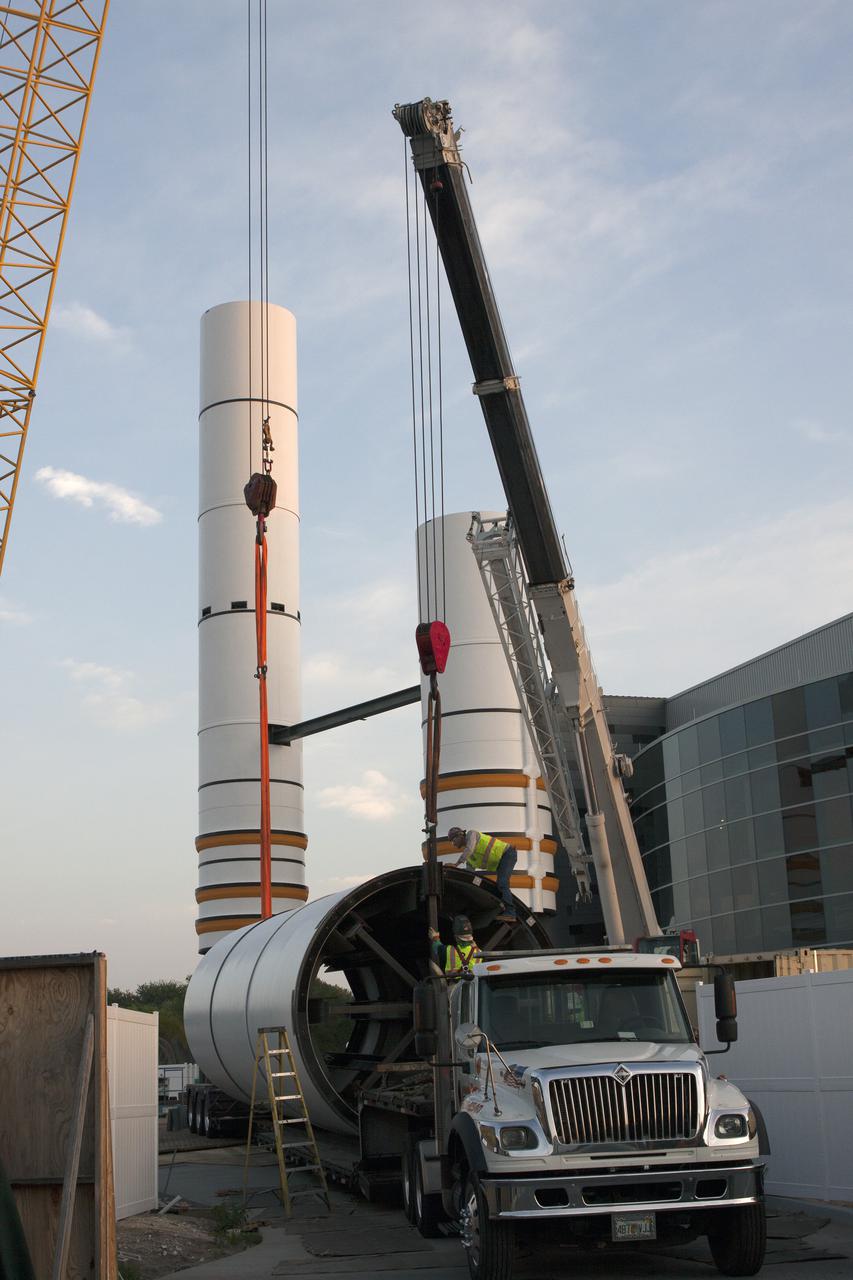 CAPE CANAVERAL, Fla. – Workers prepare to lift a segment for a set of twin, full-size replica Solid Rocket Boosters SRBs in front of the Space Shuttle Atlantis exhibit under construction at the Kennedy Space Center Visitor Complex in Florida. Atlantis is housed in the building behind the SRB stack. An external tank replica will be added later to the middle of the SRBs to complete the display. The SRBs stand 150 feet tall, while the external tank will reach 184 feet when it is finished. The shuttle was mounted to the stack and depended on the power of the SRBs to lift it off the launch pad and start it on its way to space. The external tank was loaded with liquid propellants for the shuttle's three main engines. Photo credit: NASA_Jim Grossmann
