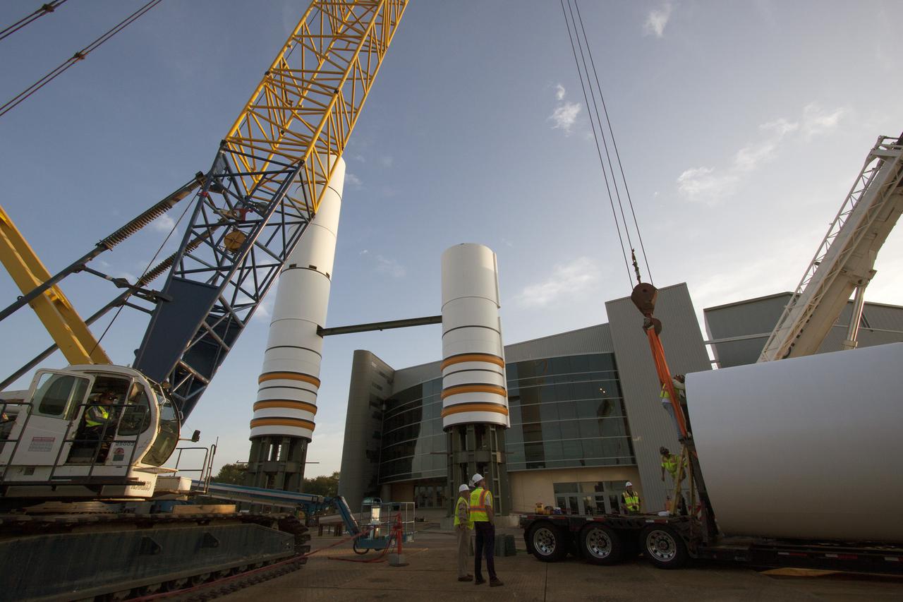 CAPE CANAVERAL, Fla. – Workers prepare to lift a segment for a set of twin, full-size replica Solid Rocket Boosters SRBs in front of the Space Shuttle Atlantis exhibit under construction at the Kennedy Space Center Visitor Complex in Florida. Atlantis is housed in the building behind the SRB stack. An external tank replica will be added later to the middle of the SRBs to complete the display. The SRBs stand 150 feet tall, while the external tank will reach 184 feet when it is finished. The shuttle was mounted to the stack and depended on the power of the SRBs to lift it off the launch pad and start it on its way to space. The external tank was loaded with liquid propellants for the shuttle's three main engines. Photo credit: NASA_Jim Grossmann
