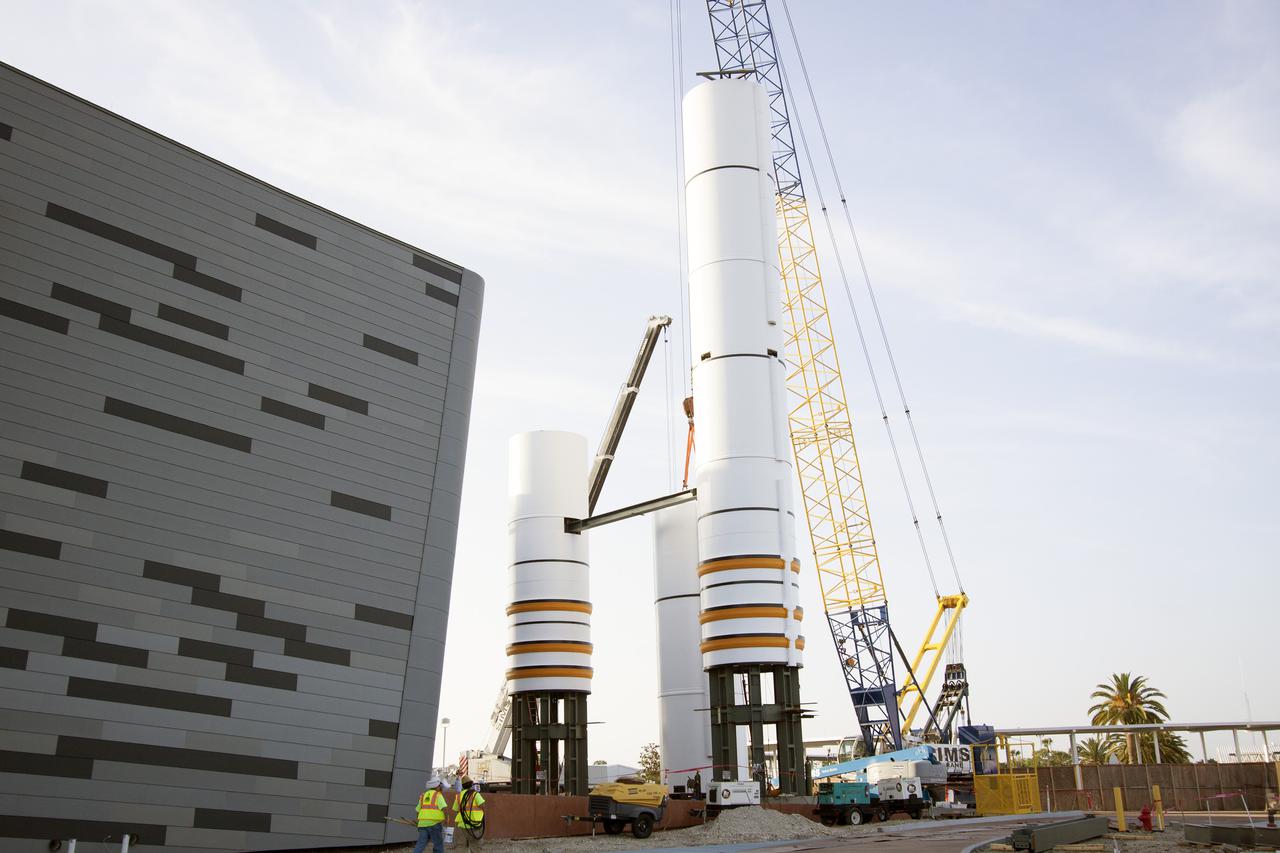 CAPE CANAVERAL, Fla. – A crane lifts a segment for a set of twin, full-size replica Solid Rocket Boosters SRBs in front of the Space Shuttle Atlantis exhibit under construction at the Kennedy Space Center Visitor Complex in Florida. Atlantis is housed in the building behind the SRB stack. An external tank replica will be added later to the middle of the SRBs to complete the display. The SRBs stand 150 feet tall, while the external tank will reach 184 feet when it is finished. The shuttle was mounted to the stack and depended on the power of the SRBs to lift it off the launch pad and start it on its way to space. The external tank was loaded with liquid propellants for the shuttle's three main engines. Photo credit: NASA_Jim Grossmann