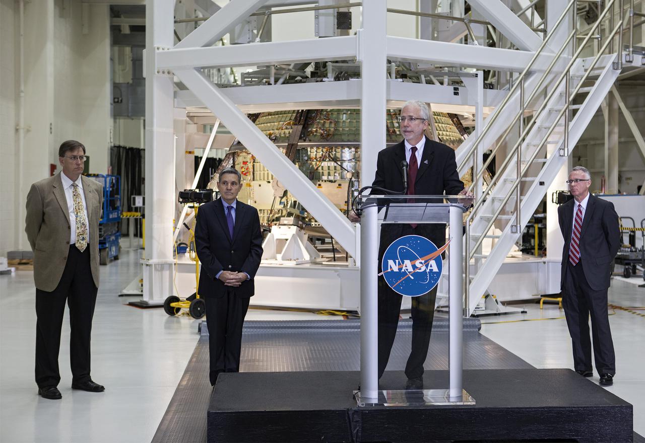 CAPE CANAVERAL, Fla. – In the Operations and Checkout Building OandC at the Kennedy Space Center in Florida, Mark Geyer, NASA's Orion program manager, speaks to news media representatives updating progress on preparing the Orion spacecraft for its first uncrewed mission, Exploration Flight Test-1 EFT-1 in 2014. The crew module is seen behind Geyer in its test stand.  Launched atop NASA's heavy-lift Space Launch System rocket, Orion is now targeted to take astronauts in a sample return mission to an asteroid as early as 2021. On the third anniversary of President Barack Obama issuing his challenge to NASA to send astronauts to an asteroid, news media representatives were given an opportunity to see up-close the Orion spacecraft which could take astronauts on such a flight. They also heard from key leaders of that effort in Kennedy's OandC where Orion's assembly is taking place. Photo credit: NASA_Kim Shiflett