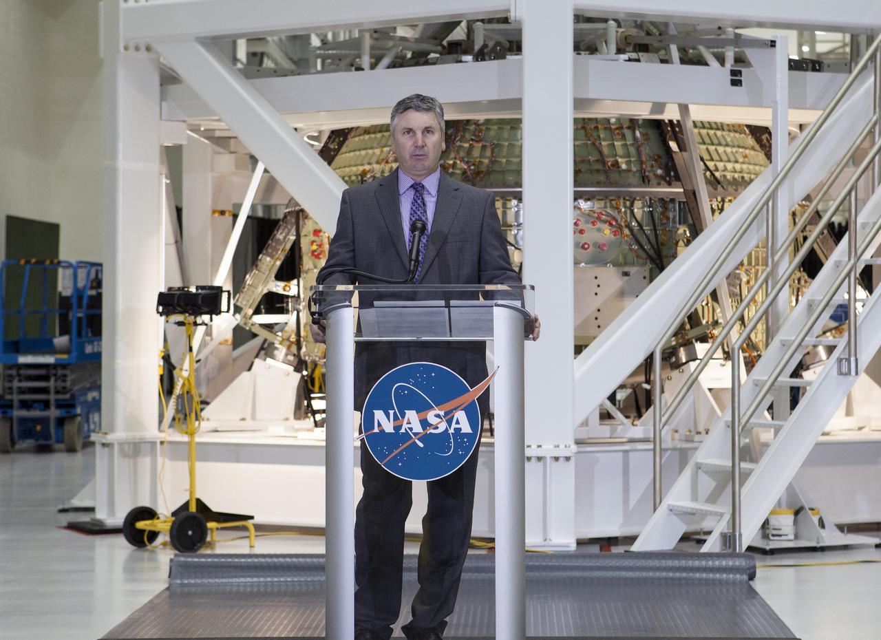CAPE CANAVERAL, Fla. – In the Operations and Checkout Building OandC at the Kennedy Space Center in Florida, Scott Colloredo, chief architect for the Ground Systems Development and Operations Program, speaks to news media representatives updating progress on preparing the Orion spacecraft for its first uncrewed mission, Exploration Flight Test-1 EFT-1 in 2014. The crew module is seen behind Colloredo in its test stand.  Launched atop NASA's heavy-lift Space Launch System rocket, Orion is now targeted to take astronauts in a sample return mission to an asteroid as early as 2021. On the third anniversary of President Barack Obama issuing his challenge to NASA to send astronauts to an asteroid, news media representatives were given an opportunity to see up-close the Orion spacecraft which could take astronauts on such a flight. They also heard from key leaders of that effort in Kennedy's OandC where Orion's assembly is taking place. Photo credit: NASA_Kim Shiflett
