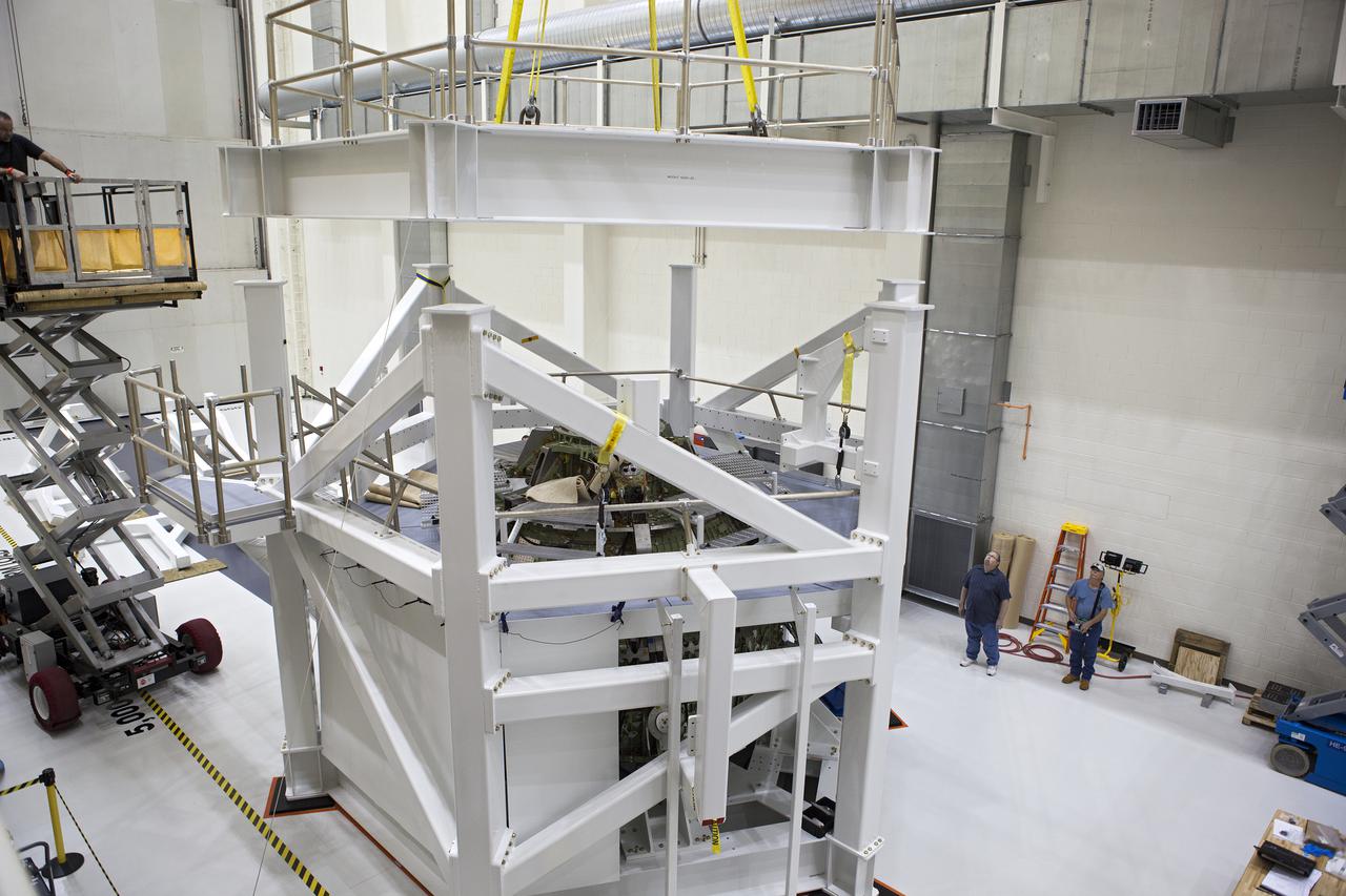 CAPE CANAVERAL, Fla. – Inside the Operations and Checkout Building high bay at NASA’s Kennedy Space Center in Florida, technicians monitor the progress as a crane lowers the top platform of a test stand for the Orion crew module. Lockheed Martin Space Systems and NASA engineers are preparing Orion for a series of static load tests that simulate the massive loads the spacecraft would experience during its mission. Orion is the exploration spacecraft designed to carry crews to space beyond low Earth orbit. It will provide emergency abort capability, sustain the crew during the space travel and provide safe re-entry from deep space return velocities. Orion’s first unpiloted test flight, Exploration Flight Test 1, is scheduled to launch in 2014 atop a Delta IV rocket. A second uncrewed flight test is scheduled for 2017 on NASA’s Space Launch System rocket. For more information, visit http:__www.nasa.gov_orion. Photo credit: NASA_Gary Thompson