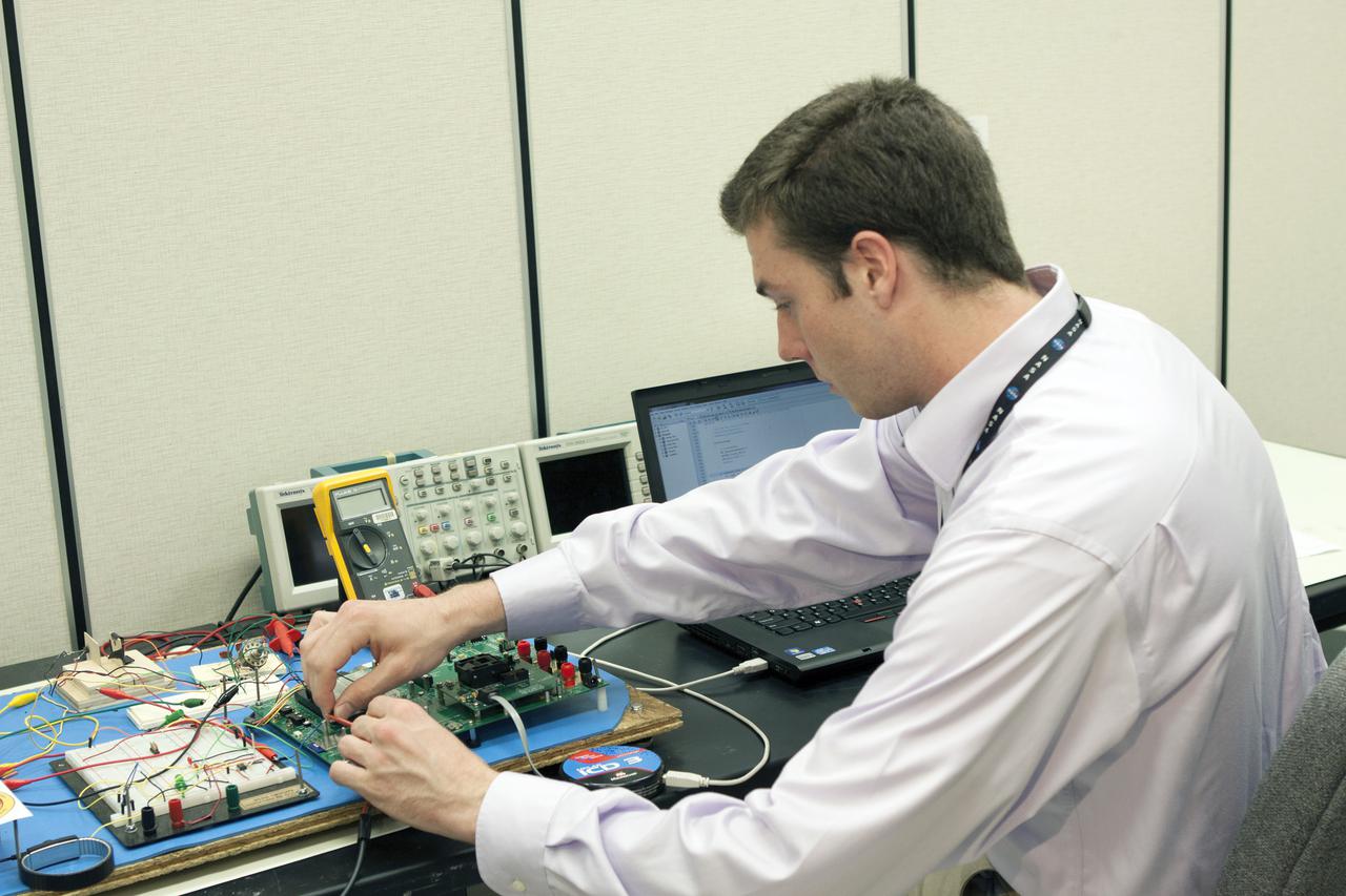 CAPE CANAVERAL, Fla. – Benjamin Plotner, an engineering intern, tests elements of a prototype of the StangSat at Kennedy Space Center before final assembly. The satellite is a small cube measuring 10 inches on all sides and will be launched on a rocket that will carry it on a suborbital mission in Mojave, Calif. Photo credit: NASA_Jim Grossmann