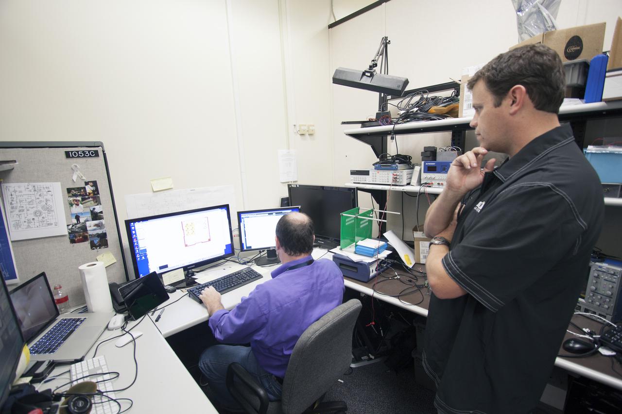 CAPE CANAVERAL, Fla. – Shaun Daly, right, and Robert Olsen test elements of a prototype of the StangSat at Kennedy Space Center before final assembly. The satellite is a small cube measuring 10 inches on all sides and will be launched on a rocket that will carry it on a suborbital mission in Mojave, Calif. Photo credit: NASA_Jim Grossmann