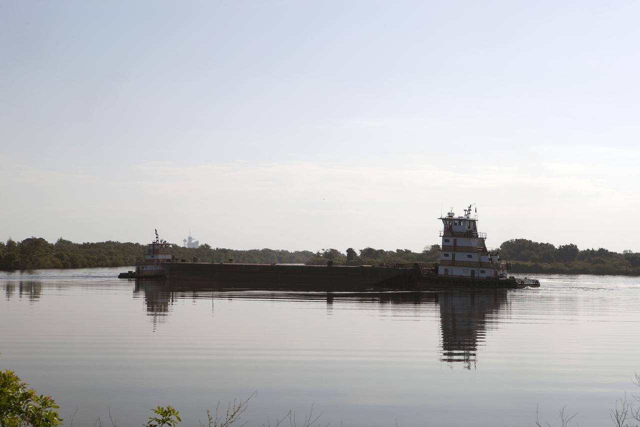CAPE CANAVERAL, Fla. – A barge arrives at the Kennedy Space Center Turn Basin to pick up an orange flight test article space shuttle external fuel tank, or ET, an ET transporter, the crew transport vehicle, crew hatch access vehicle, solid rocket booster, or SRB, aft skirt and SRB frustum for the first leg of their journey from NASA's Kennedy Space Center in Florida to the Wings of Dreams Aviation Museum located at Keystone Heights Airport in North Central Florida.   Thousands of unique space shuttle era artifacts are being allocated to facilities across the country for their new missions to educate and inspire America's next generation of explorers. Photo credit: NASA_Dimitri Gerondidakis