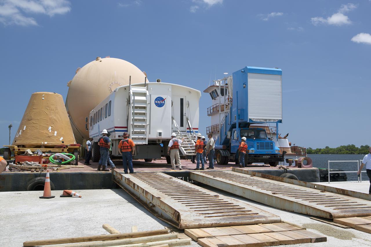 CAPE CANAVERAL, Fla. – A space shuttle orange flight test article external fuel tank, or ET, an ET transporter, crew hatch access vehicle, crew transport vehicle, solid rocket booster, or SRB, aft skirt and SRB frustum are loaded onto a barge for the first leg of their journey from NASA's Kennedy Space Center in Florida to the Wings of Dreams Aviation Museum located at Keystone Heights Airport in North Central Florida.   Thousands of unique space shuttle era artifacts are being allocated to facilities across the country for their new missions to educate and inspire America's next generation of explorers. Photo credit: NASA_Dimitri Gerondidakis