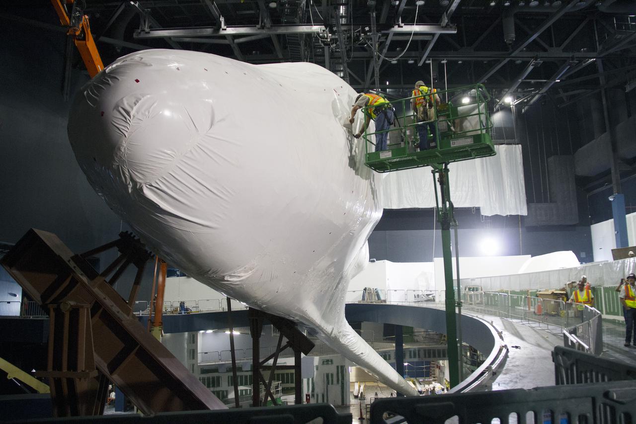 CAPE CANAVERAL, Fla. -- At the Kennedy Space Center Visitor Complex in Florida, construction crews begin removing 16,000 square feet of plastic shrink-wrap from the space shuttle Atlantis. The spacecraft was enclosed in the plastic shrink-wrap since November of last year to protect the artifact from dust and debris during construction of the 90,000-square-foot facility. Last November, the space shuttle Atlantis made its historic final journey to its new home, traveling 10 miles from the Kennedy Space Center's Vehicle Assembly Building to the spaceport's visitor complex. The new $100 million 'Space Shuttle Atlantis' facility will include interactive exhibits that tell the story of the 30-year Space Shuttle Program and highlights the future of space exploration. The 'Space Shuttle Atlantis' exhibit scheduled to open June 29, 2013.Photo credit: NASA_Cory Huston