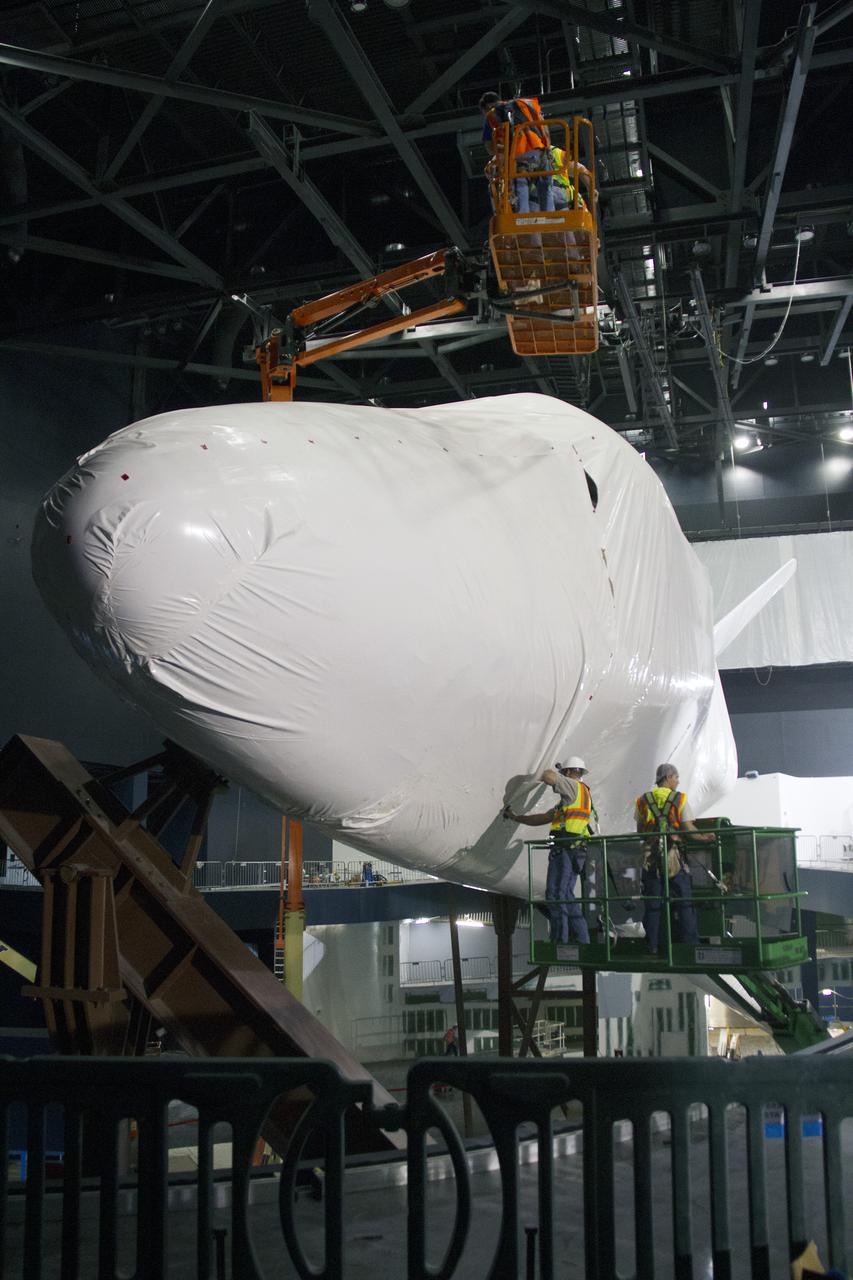 CAPE CANAVERAL, Fla. -- At the Kennedy Space Center Visitor Complex in Florida, construction crews begin removing 16,000 square feet of plastic shrink-wrap from the space shuttle Atlantis. The spacecraft was enclosed in the plastic shrink-wrap since November of last year to protect the artifact from dust and debris during construction of the 90,000-square-foot facility. Last November, the space shuttle Atlantis made its historic final journey to its new home, traveling 10 miles from the Kennedy Space Center's Vehicle Assembly Building to the spaceport's visitor complex. The new $100 million 'Space Shuttle Atlantis' facility will include interactive exhibits that tell the story of the 30-year Space Shuttle Program and highlights the future of space exploration. The 'Space Shuttle Atlantis' exhibit scheduled to open June 29, 2013.Photo credit: NASA_Cory Huston