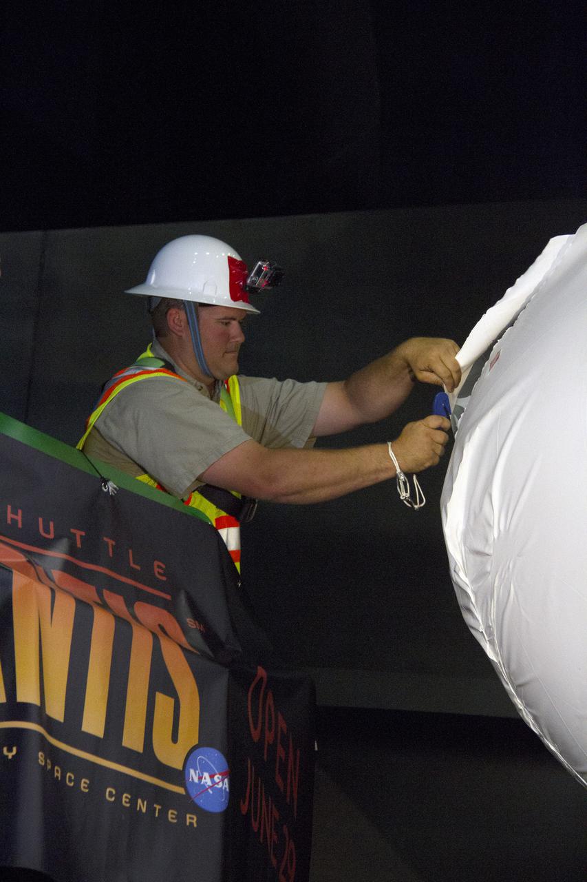 CAPE CANAVERAL, Fla. -- At the Kennedy Space Center Visitor Complex in Florida, a construction worker begins removing 16,000 square feet of plastic shrink-wrap from the space shuttle Atlantis. The spacecraft was enclosed in the plastic shrink-wrap since November of last year to protect the artifact from dust and debris during construction of the 90,000-square-foot facility. Last November, the space shuttle Atlantis made its historic final journey to its new home, traveling 10 miles from the Kennedy Space Center's Vehicle Assembly Building to the spaceport's visitor complex. The new $100 million 'Space Shuttle Atlantis' facility will include interactive exhibits that tell the story of the 30-year Space Shuttle Program and highlights the future of space exploration. The 'Space Shuttle Atlantis' exhibit scheduled to open June 29, 2013.Photo credit: NASA_Cory Huston