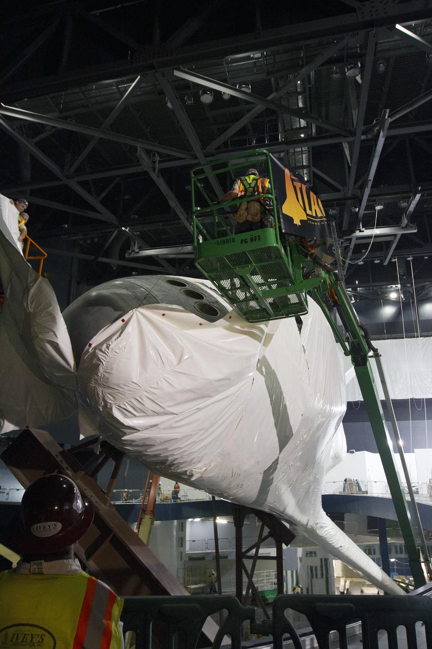 CAPE CANAVERAL, Fla. -- At the Kennedy Space Center Visitor Complex in Florida, construction crews begin removing 16,000 square feet of plastic shrink-wrap from the space shuttle Atlantis. The spacecraft was enclosed in the plastic shrink-wrap since November of last year to protect the artifact from dust and debris during construction of the 90,000-square-foot facility. Last November, the space shuttle Atlantis made its historic final journey to its new home, traveling 10 miles from the Kennedy Space Center's Vehicle Assembly Building to the spaceport's visitor complex. The new $100 million 'Space Shuttle Atlantis' facility will include interactive exhibits that tell the story of the 30-year Space Shuttle Program and highlights the future of space exploration. The 'Space Shuttle Atlantis' exhibit scheduled to open June 29, 2013.Photo credit: NASA_Cory Huston