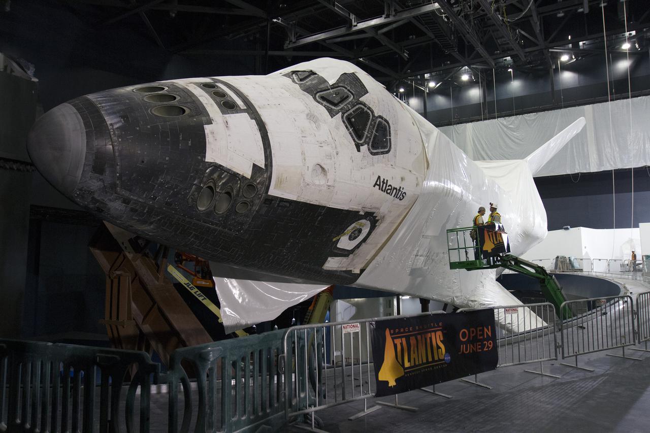 CAPE CANAVERAL, Fla. -- At the Kennedy Space Center Visitor Complex in Florida, the space shuttle Atlantis' forward section has been uncovered as construction crews begin removing 16,000 square feet of plastic shrink-wrap from the spacecraft. The shuttle was enclosed in the plastic shrink-wrap since November of last year to protect the artifact from dust and debris during construction of the 90,000-square-foot facility. Last November, the space shuttle Atlantis made its historic final journey to its new home, traveling 10 miles from the Kennedy Space Center's Vehicle Assembly Building to the spaceport's visitor complex. The new $100 million 'Space Shuttle Atlantis' facility will include interactive exhibits that tell the story of the 30-year Space Shuttle Program and highlights the future of space exploration. The 'Space Shuttle Atlantis' exhibit scheduled to open June 29, 2013.Photo credit: NASA_Cory Huston
