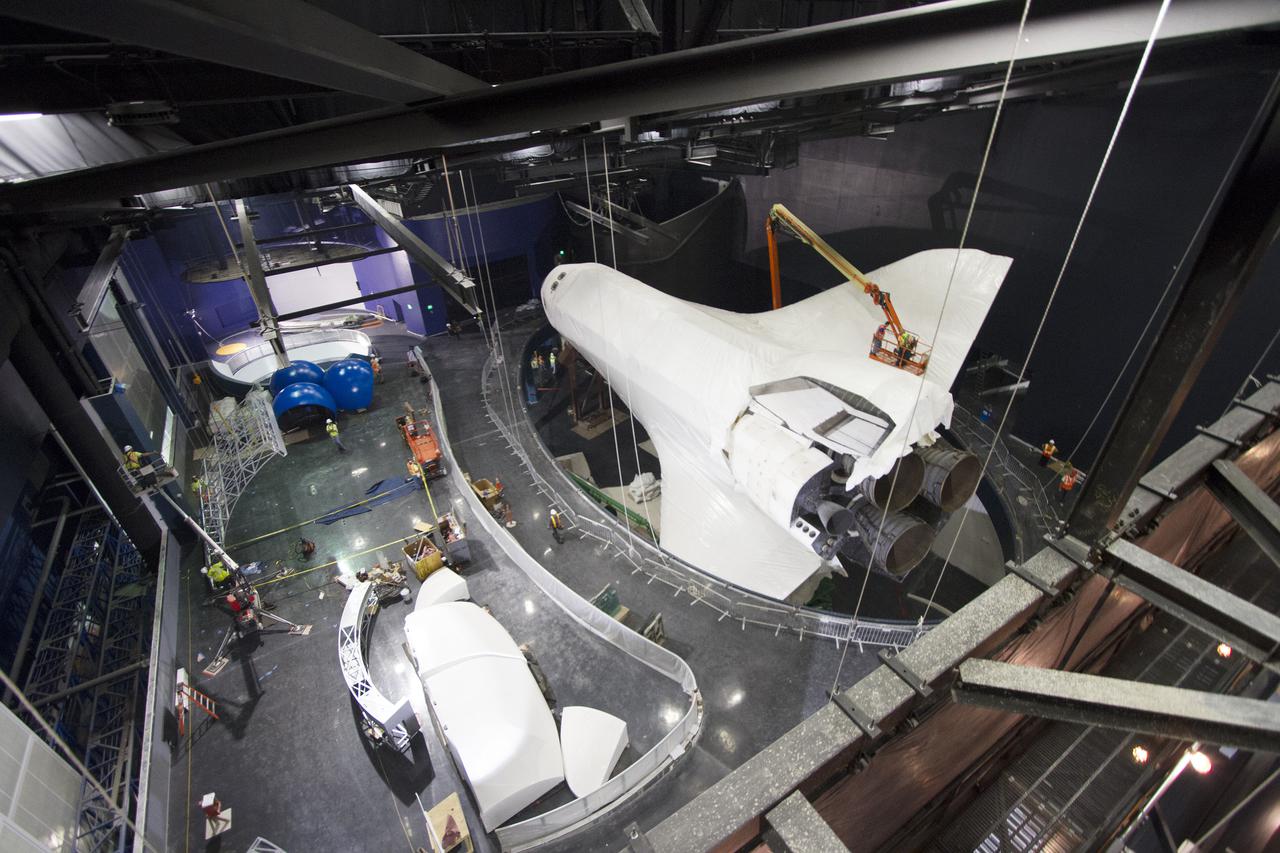 CAPE CANAVERAL, Fla. -- At the Kennedy Space Center Visitor Complex in Florida, construction crews remove 16,000 square feet of plastic shrink-wrap from the space shuttle Atlantis. The spacecraft was enclosed in the plastic shrink-wrap since November of last year to protect the artifact from dust and debris during construction of the 90,000-square-foot facility. Last November, the space shuttle Atlantis made its historic final journey to its new home, traveling 10 miles from the Kennedy Space Center's Vehicle Assembly Building to the spaceport's visitor complex. The new $100 million 'Space Shuttle Atlantis' facility will include interactive exhibits that tell the story of the 30-year Space Shuttle Program and highlights the future of space exploration. The 'Space Shuttle Atlantis' exhibit scheduled to open June 29, 2013.Photo credit: NASA_ Cory Huston
