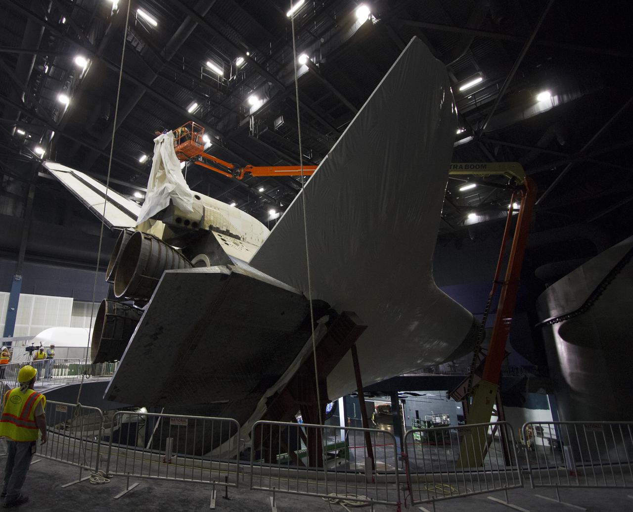 CAPE CANAVERAL, Fla. -- At the Kennedy Space Center Visitor Complex in Florida, construction crews remove 16,000 square feet of plastic shrink-wrap from the space shuttle Atlantis. The spacecraft was enclosed in the plastic shrink-wrap since November of last year to protect the artifact from dust and debris during construction of the 90,000-square-foot facility. Last November, the space shuttle Atlantis made its historic final journey to its new home, traveling 10 miles from the Kennedy Space Center's Vehicle Assembly Building to the spaceport's visitor complex. The new $100 million 'Space Shuttle Atlantis' facility will include interactive exhibits that tell the story of the 30-year Space Shuttle Program and highlights the future of space exploration. The 'Space Shuttle Atlantis' exhibit scheduled to open June 29, 2013.Photo credit: NASA_ Cory Huston