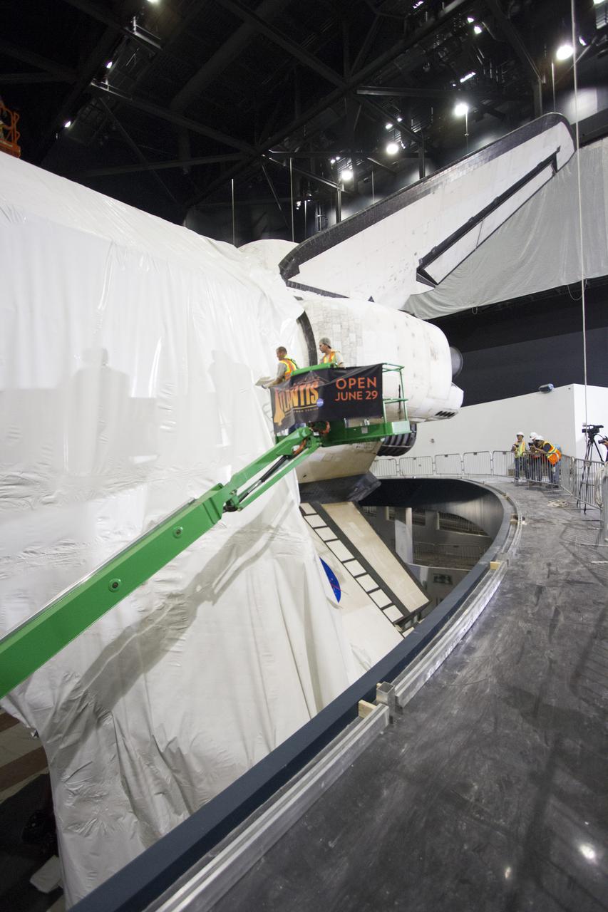 CAPE CANAVERAL, Fla. -- At the Kennedy Space Center Visitor Complex in Florida, construction crews remove 16,000 square feet of plastic shrink-wrap from the space shuttle Atlantis. The spacecraft was enclosed in the plastic shrink-wrap since November of last year to protect the artifact from dust and debris during construction of the 90,000-square-foot facility. Last November, the space shuttle Atlantis made its historic final journey to its new home, traveling 10 miles from the Kennedy Space Center's Vehicle Assembly Building to the spaceport's visitor complex. The new $100 million 'Space Shuttle Atlantis' facility will include interactive exhibits that tell the story of the 30-year Space Shuttle Program and highlights the future of space exploration. The 'Space Shuttle Atlantis' exhibit scheduled to open June 29, 2013.Photo credit: NASA_ Cory Huston
