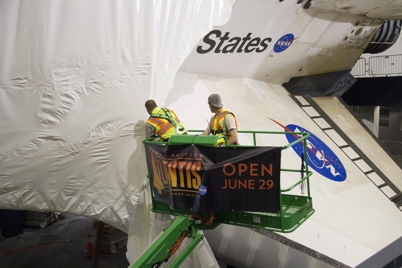 CAPE CANAVERAL, Fla. -- At the Kennedy Space Center Visitor Complex in Florida, construction crews remove 16,000 square feet of plastic shrink-wrap from the space shuttle Atlantis. The spacecraft was enclosed in the plastic shrink-wrap since November of last year to protect the artifact from dust and debris during construction of the 90,000-square-foot facility. Last November, the space shuttle Atlantis made its historic final journey to its new home, traveling 10 miles from the Kennedy Space Center's Vehicle Assembly Building to the spaceport's visitor complex. The new $100 million 'Space Shuttle Atlantis' facility will include interactive exhibits that tell the story of the 30-year Space Shuttle Program and highlights the future of space exploration. The 'Space Shuttle Atlantis' exhibit scheduled to open June 29, 2013.Photo credit: NASA_ Cory Huston