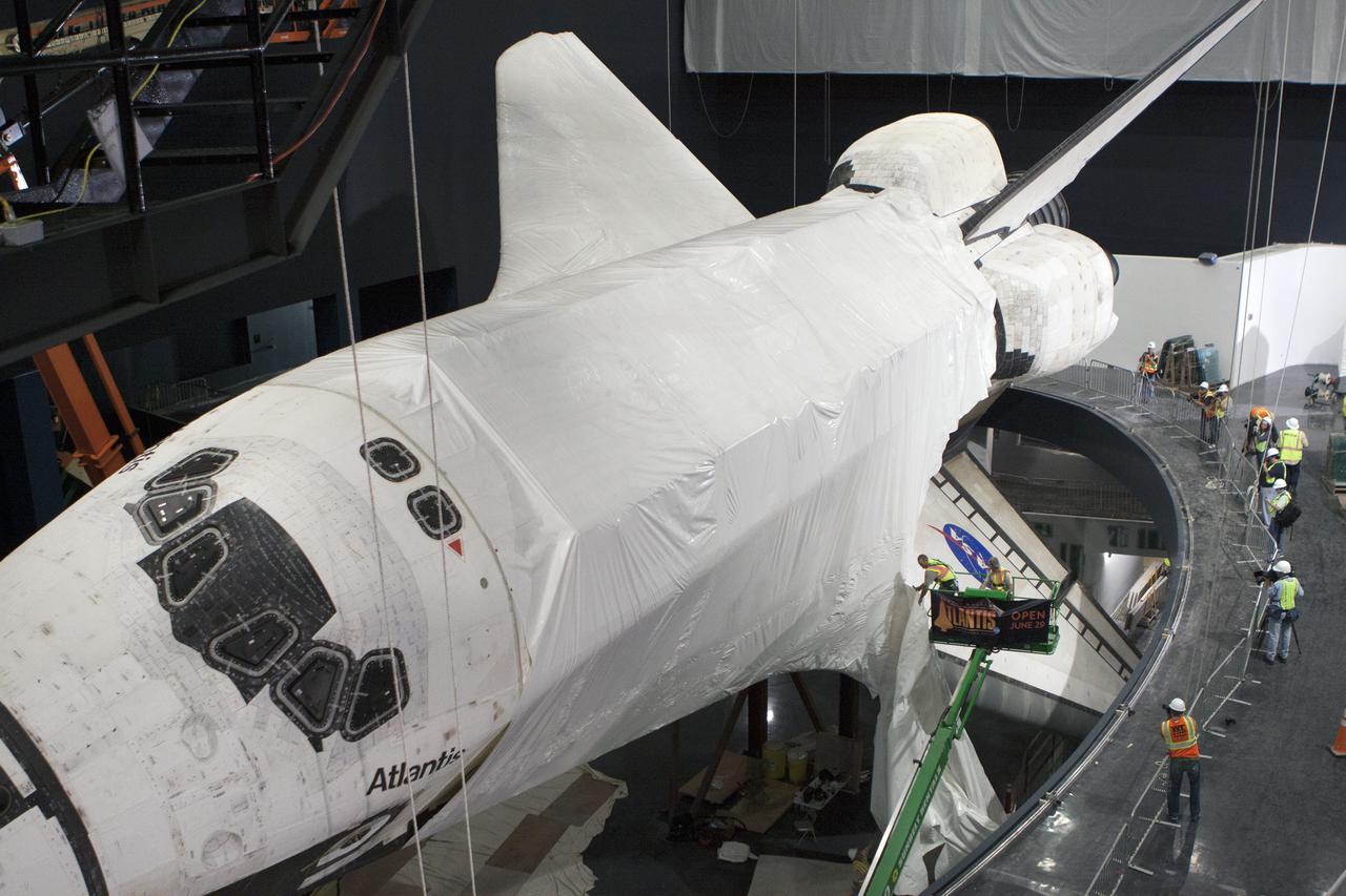 CAPE CANAVERAL, Fla. -- At the Kennedy Space Center Visitor Complex in Florida, construction crews remove 16,000 square feet of plastic shrink-wrap from the space shuttle Atlantis. The spacecraft was enclosed in the plastic shrink-wrap since November of last year to protect the artifact from dust and debris during construction of the 90,000-square-foot facility. Last November, the space shuttle Atlantis made its historic final journey to its new home, traveling 10 miles from the Kennedy Space Center's Vehicle Assembly Building to the spaceport's visitor complex. The new $100 million 'Space Shuttle Atlantis' facility will include interactive exhibits that tell the story of the 30-year Space Shuttle Program and highlights the future of space exploration. The 'Space Shuttle Atlantis' exhibit scheduled to open June 29, 2013.Photo credit: NASA_Kim Shiflett