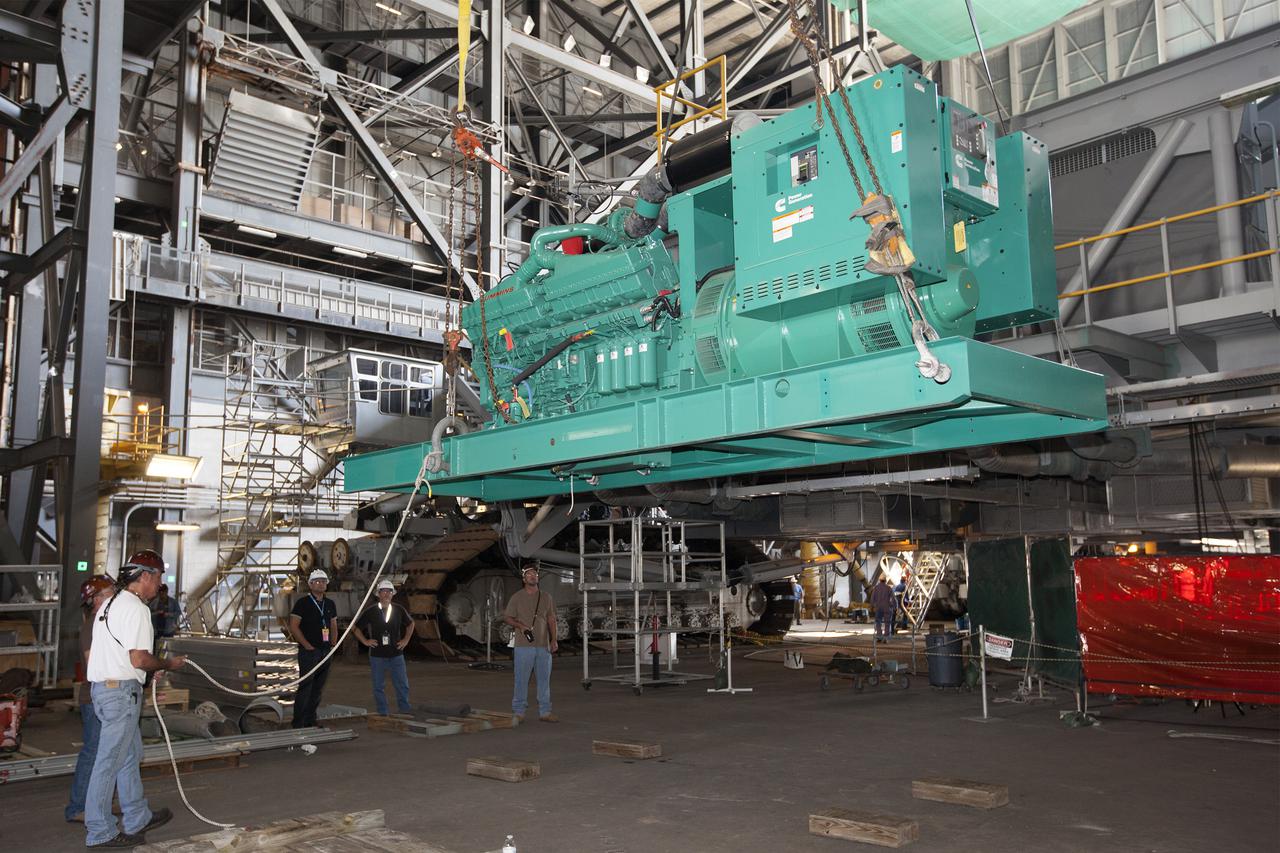 CAPE CANAVERAL, Fla. – Inside the Vehicle Assembly Building at NASA’s Kennedy Space Center in Florida, technicians monitor the progress as a large crane lifts a new Cummins engine and generator for installation inside crawler-transporter 1 CT-1. The Apollo era diesel engines were removed so that the new engine can be installed.     Work continues in high bay 3 to upgrade CT-1 as part of its general maintenance and could be available to carry commercial launch vehicles to the launch pad. The crawler-transporters were used to carry the mobile launcher platform and space shuttle to Launch Complex 39 for space shuttle launches for 30 years.  Photo credit: NASA_Kim Shiflett
