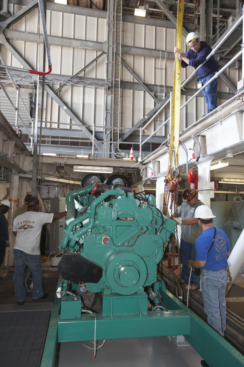 CAPE CANAVERAL, Fla. – Inside the Vehicle Assembly Building at NASA’s Kennedy Space Center in Florida, technicians begin the work to secure a new Cummins engine and generator inside crawler-transporter 1 CT-1. The Apollo era diesel engines were removed so that the new engine can be installed.      Work continues in high bay 3 to upgrade CT-1 as part of its general maintenance and could be available to carry commercial launch vehicles to the launch pad. The crawler-transporters were used to carry the mobile launcher platform and space shuttle to Launch Complex 39 for space shuttle launches for 30 years.  Photo credit: NASA_Kim Shiflett