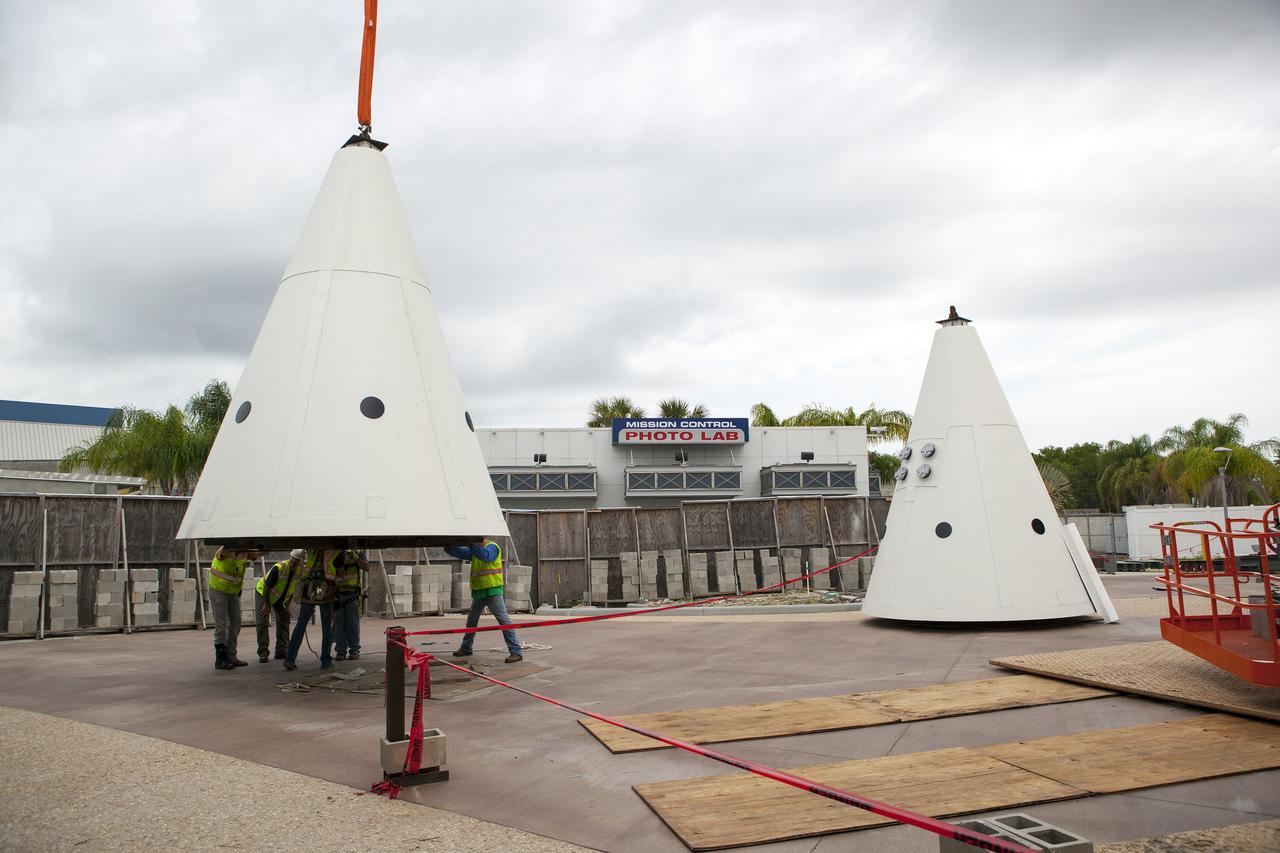 CAPE CANAVERAL, Fla. – Workers prepare to lift a nose cone to top out one of a pair of replica space shuttle solid rocket boosters at the entry of the space shuttle Atlantis attraction under construction at the Kennedy Space Center Visitor Complex. Workers will use cranes to place the nose cones atop each of the model boosters. Photo credit: NASA_Dmitri Gerondidakis