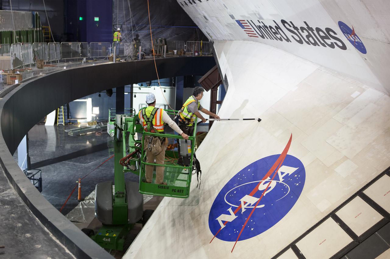CAPE CANAVERAL, Fla. – CAPE CANAVERAL, Fla. - Construction crews clean space shuttle Atlantis following the removal of 16,000 square feet of plastic shrink-wrap that enclosed the spacecraft since November of last year to protect the artifact from dust and debris during construction of the 90,000-square-foot facility. The new $100 million 'Space Shuttle Atlantis' facility will include interactive exhibits that tell the story of the 30-year Space Shuttle Program and highlights the future of space exploration. The 'Space Shuttle Atlantis' exhibit scheduled to open June 29, 2013. Photo credit: NASA_ Dmitri Gerondidakis