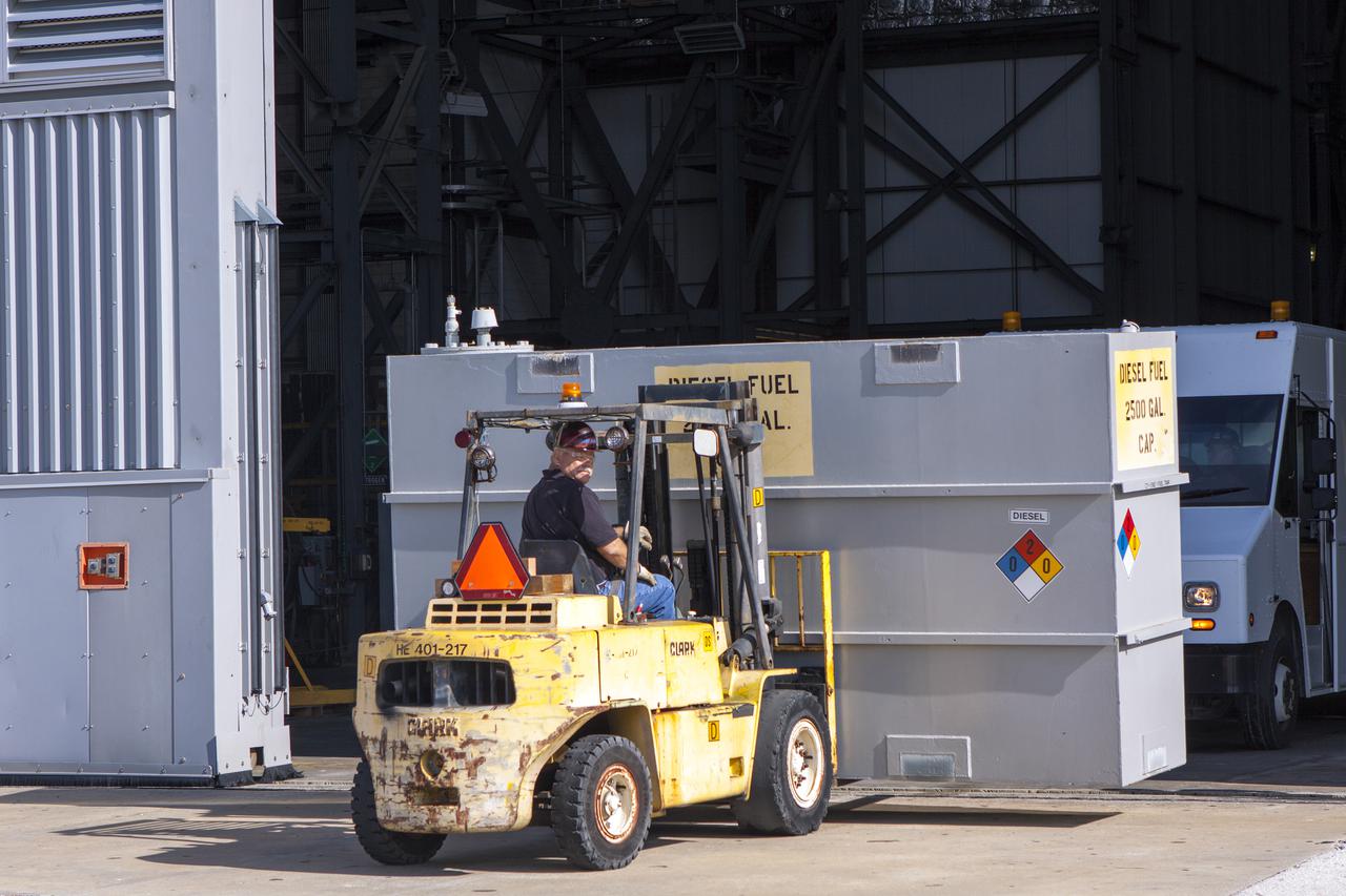 CAPE CANAVERAL, Fla. – In front of the Vehicle Assembly Building at NASA’s Kennedy Space Center in Florida, a technician uses a forklift to move a fuel tank after it was removed from crawler-transporter 1 CT-1 in high bay 3. The fuel tank will be transporter to the Wiltech facility at Kennedy for cleaning and inspection.  Work continues in high bay 3 to upgrade CT-1 as part of its general maintenance. CT-1 could be available to carry commercial launch vehicles to the launch pad. The crawler-transporters were used to carry the mobile launcher platform and space shuttle to Launch Complex 39 for space shuttle launches for 30 years.  Photo credit: NASA_Jim Grossman