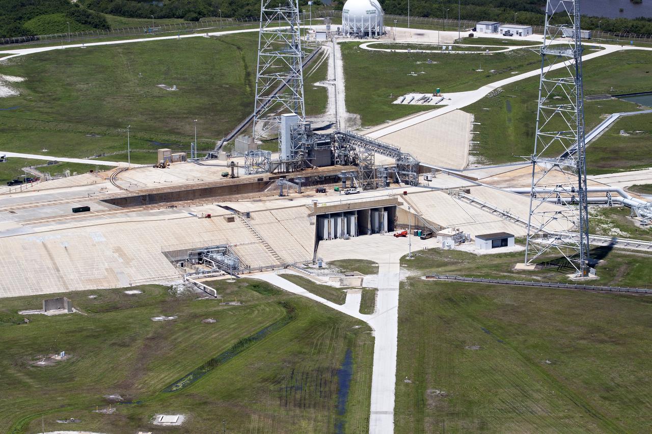 CAPE CANAVERAL, Fla. – An aerial view shows construction progress at Launch Pad 39B at NASA’s Kennedy Space Center in Florida. A new elevator has been constructed on the surface of the pad and the crawlerway leading up to the surface is being repaired. Repairs also are being made to the crawler track panels and catacomb roof below on either side of the flame trench. Also in view are two of the three tall lightning towers that surround the pad.  Upgrades are underway at Pad B and other facilities in the Launch Complex 39 area. The Ground Systems Development and Operations, or GSDO, Program office at Kennedy is leading the center’s transformation from a historically government-only launch complex to a spaceport that can safely handle a variety of rockets and spacecraft, including NASA’s Space Launch System. For more information about GSDO, visit: http:__go.nasa.gov_groundsystems.  Photo credit: NASA_Kim Shiflett