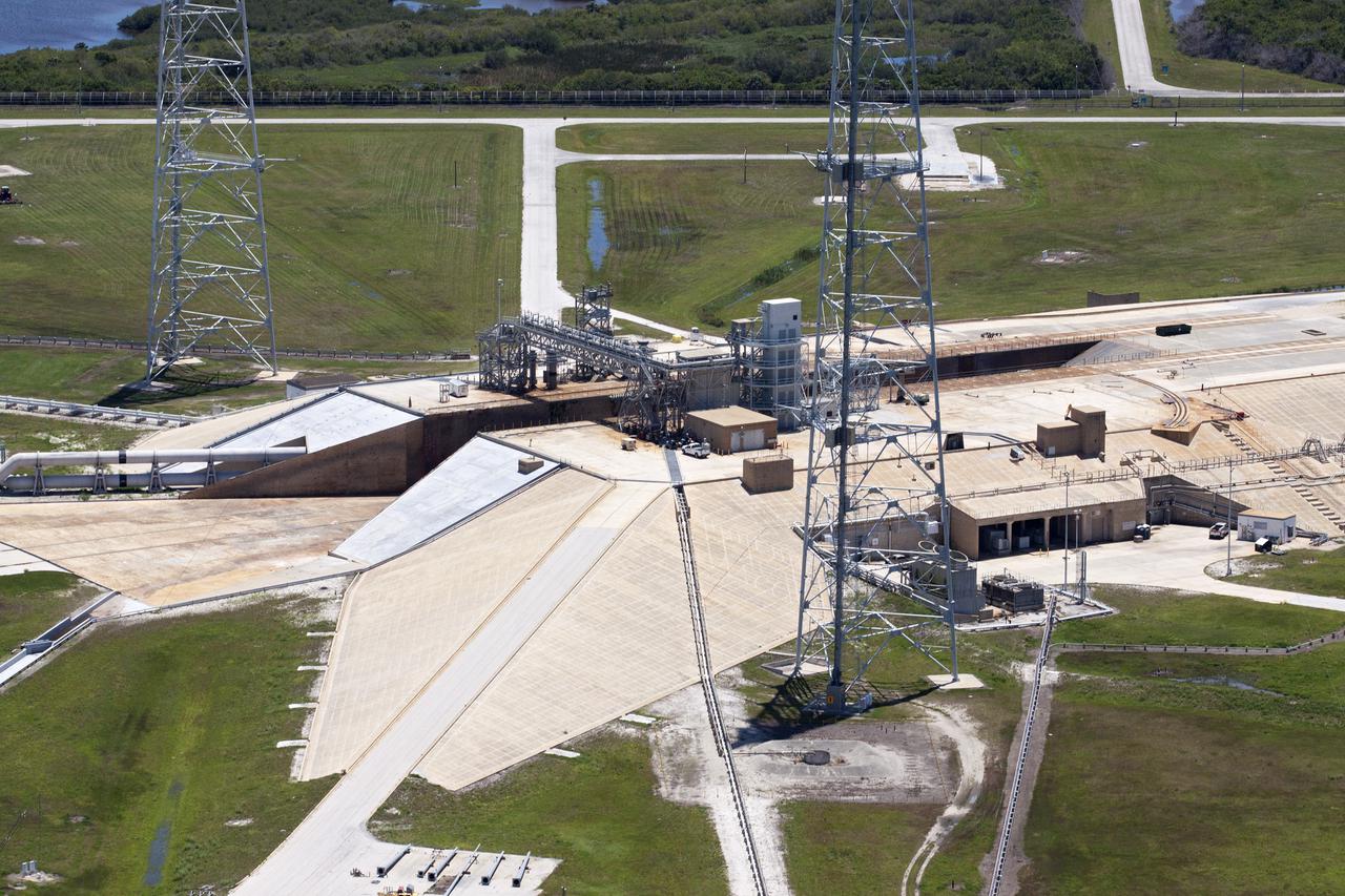 CAPE CANAVERAL, Fla. – An aerial view shows construction progress at Launch Pad 39B at NASA’s Kennedy Space Center in Florida. A new elevator has been constructed on the surface of the pad and the crawlerway leading up to the surface is being repaired. Repairs also are being made to the crawler track panels and catacomb roof below on either side of the flame trench. Also in view are two of the three tall lightning towers that surround the pad.  Upgrades are underway at Pad B and other facilities in the Launch Complex 39 area. The Ground Systems Development and Operations, or GSDO, Program office at Kennedy is leading the center’s transformation from a historically government-only launch complex to a spaceport that can safely handle a variety of rockets and spacecraft, including NASA’s Space Launch System. For more information about GSDO, visit: http:__go.nasa.gov_groundsystems.  Photo credit: NASA_Kim Shiflett