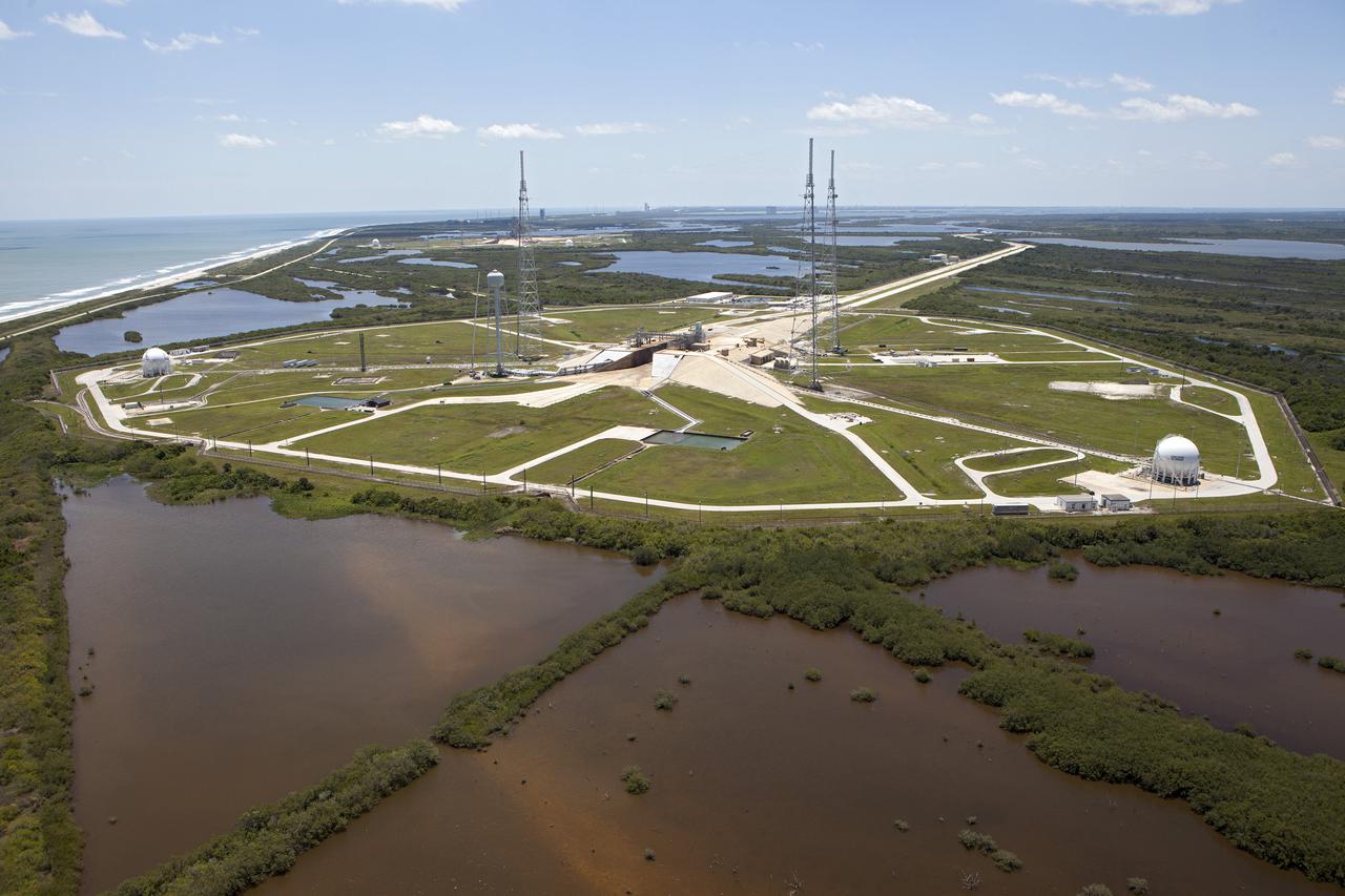 CAPE CANAVERAL, Fla. – An aerial view, from the west looking toward the east, shows the entire Launch Pad 39B area at NASA’s Kennedy Space Center in Florida. A new elevator has been constructed on the surface of the pad and the crawlerway leading up to the surface is being repaired. Repairs also are being made to the crawler track panels and catacomb roof below on either side of the flame trench. Also in view are the water tower and the three tall lightning towers that surround the pad. To the east is the Atlantic Ocean.  Upgrades are underway at Pad B and other facilities in the Launch Complex 39 area. The Ground Systems Development and Operations, or GSDO, Program office at Kennedy is leading the center’s transformation from a historically government-only launch complex to a spaceport that can safely handle a variety of rockets and spacecraft, including NASA’s Space Launch System. For more information about GSDO, visit: http:__go.nasa.gov_groundsystems.  Photo credit: NASA_Kim Shiflett