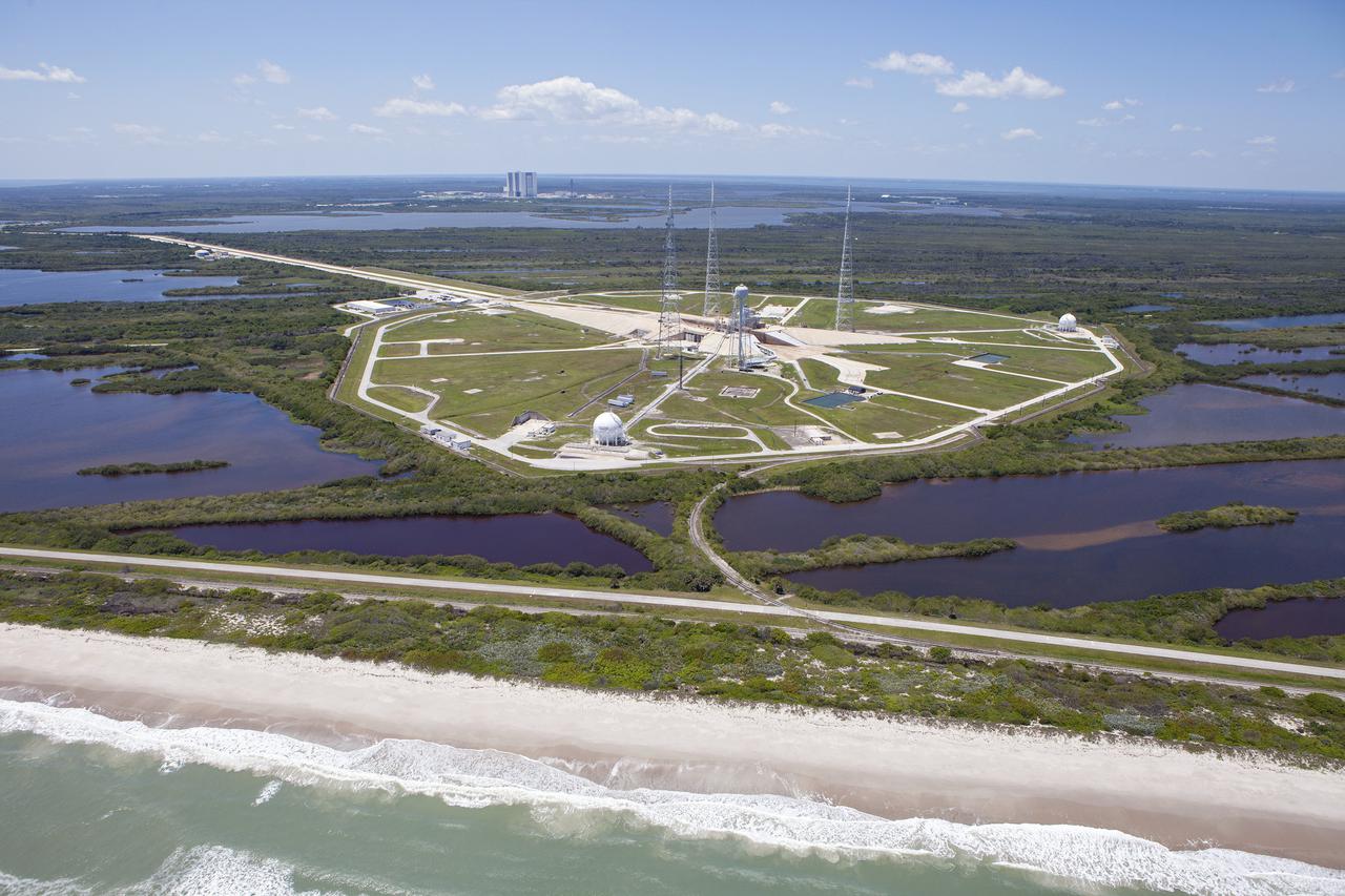 CAPE CANAVERAL, Fla. – An aerial view, from the east looking toward the west, shows the entire Launch Pad 39B area at NASA’s Kennedy Space Center in Florida. A new elevator has been constructed on the surface of the pad and the crawlerway leading up to the surface is being repaired. Repairs also are being made to the crawler track panels and catacomb roof below on either side of the flame trench. Also in view are the water tower and the three tall lightning towers that surround the pad. To the left, in the background is the Vehicle Assembly Building. In the foreground is the shoreline of the Atlantic Ocean.  Upgrades are underway at Pad B and other facilities in the Launch Complex 39 area. The Ground Systems Development and Operations, or GSDO, Program office at Kennedy is leading the center’s transformation from a historically government-only launch complex to a spaceport that can safely handle a variety of rockets and spacecraft, including NASA’s Space Launch System. For more information about GSDO, visit: http:__go.nasa.gov_groundsystems.  Photo credit: NASA_Kim Shiflett