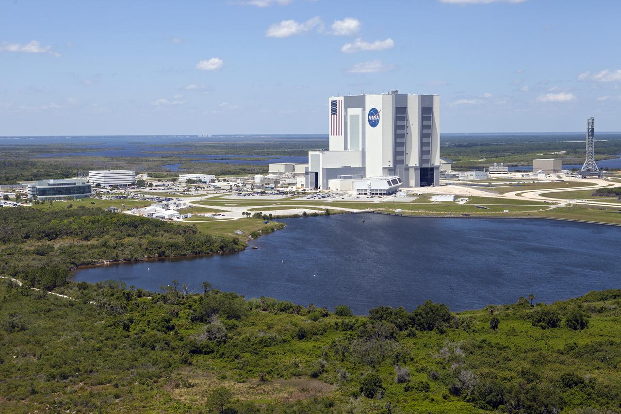 CAPE CANAVERAL, Fla. – An aerial view of the Vehicle Assembly Building, or VAB, and other buildings in the Launch Complex 39 area at NASA’s Kennedy Space Center in Florida. The Launch Control Center is in front of the VAB. To the right is the mobile launcher that will be used to transport NASA’s Space Launch System rocket and the Orion crew capsule to Launch Pad 39B.     Upgrades are underway at Pad B and other facilities in the Launch Complex 39 area. The Ground Systems Development and Operations, or GSDO, Program office at Kennedy is leading the center’s transformation from a historically government-only launch complex to a spaceport that can safely handle a variety of rockets and spacecraft, including NASA’s Space Launch System. For more information about GSDO, visit: http:__go.nasa.gov_groundsystems.  Photo credit: NASA_Kim Shiflett