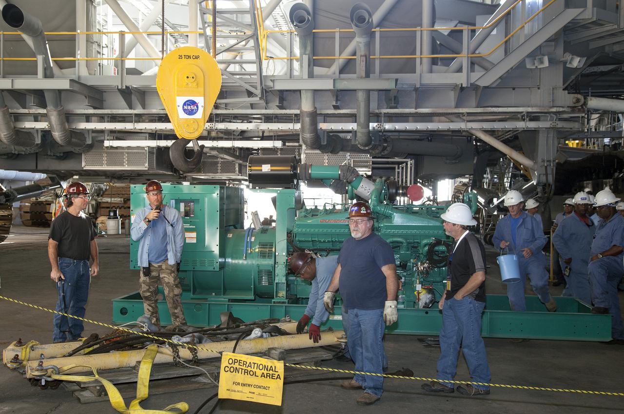 CAPE CANAVERAL, Fla. – Inside the Vehicle Assembly Building at NASA’s Kennedy Space Center in Florida, technicians prepare a new generator to be lifted by crane for installation in crawler-transporter 1, or CT-1.    Work continues in high bay 3 to upgrade CT-1 as part of its general maintenance. CT-1 could be available to carry commercial launch vehicles to the launch pad. The crawler-transporters were used to carry the mobile launcher platform and space shuttle to Launch Complex 39 for space shuttle launches for 30 years.  Photo credit: NASA_Daniel Casper