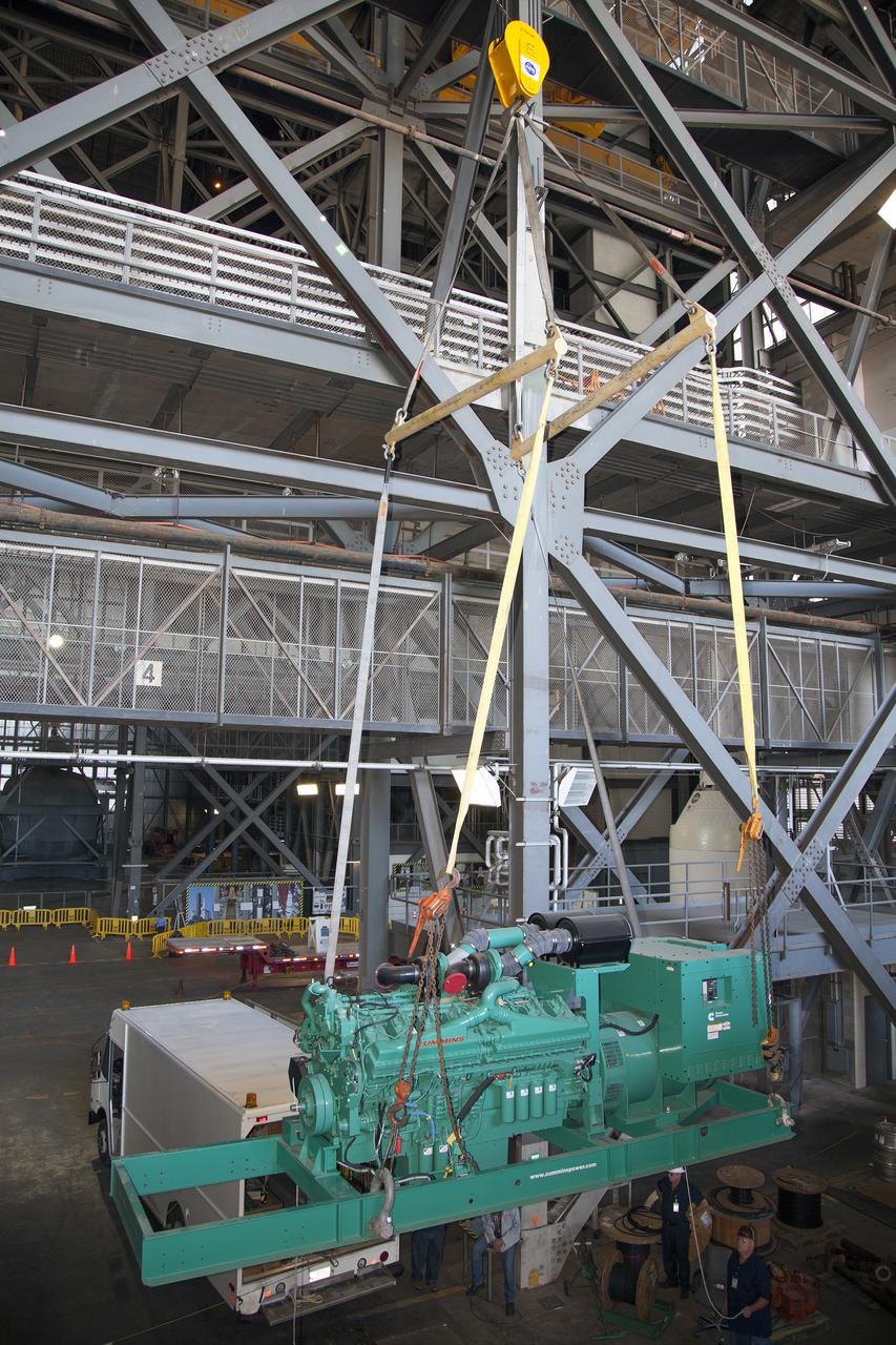 CAPE CANAVERAL, Fla. – Inside the Vehicle Assembly Building at NASA’s Kennedy Space Center in Florida, a large crane is used to lift a new generator for installation in crawler-transporter 1, or CT-1.    Work continues in high bay 3 to upgrade CT-1 as part of its general maintenance. CT-1 could be available to carry commercial launch vehicles to the launch pad. The crawler-transporters were used to carry the mobile launcher platform and space shuttle to Launch Complex 39 for space shuttle launches for 30 years.  Photo credit: NASA_Daniel Casper