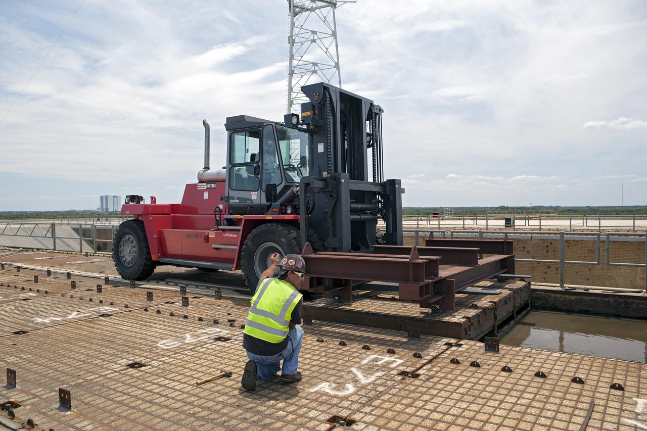 CAPE CANAVERAL, Fla. – At Launch Pad 39B at NASA’s Kennedy Space Center in Florida, a construction worker prepares a crawler track panel on the pad’s surface for removal. The concrete surface beneath the panels and the catacomb roof below will be inspected for water damage and repaired.  There are 176 panels, each weighing about 30,000 pounds that will be removed. Launch Pad 39B is being refurbished to support NASA’s Space Launch System and other launch vehicles. The Ground Systems Development and Operations, or GSDO, Program office at Kennedy is leading the center’s transformation to safely handle a variety of rockets and spacecraft. For more information about GSDO, visit: http:__go.nasa.gov_groundsystems.  Photo credit: NASA_Dimitri Gerondidakis