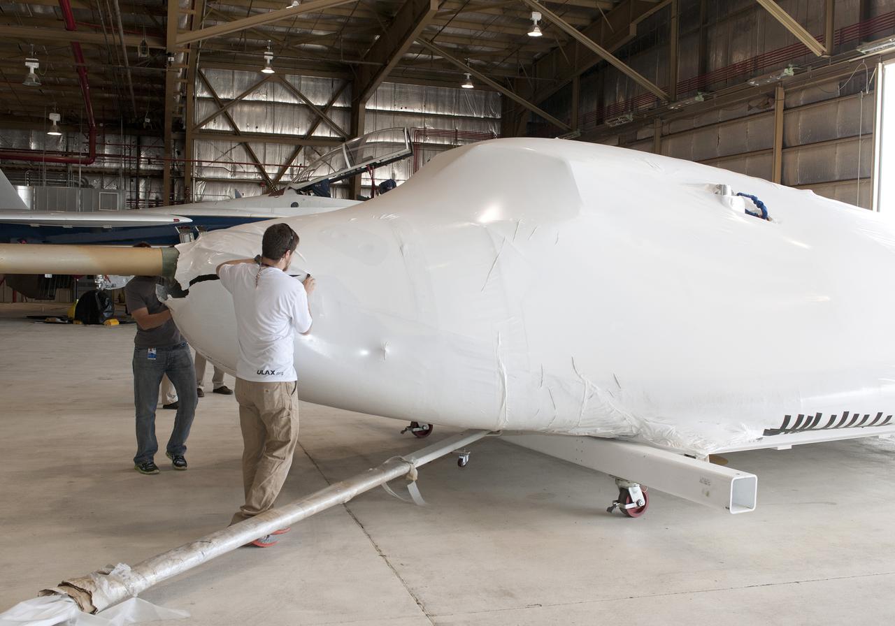 Edwards, Calif. – ED-0144-01 - Plastic wrapping that protected the Sierra Nevada Corporation, or SNC, Dream Chaser flight test vehicle during its transport from Colorado is carefully removed by SNC employee Will Armijo following the craft's arrival at NASA's Dryden Flight Research Center in southern California. The prototype space access vehicle will undergo ground and approach-and-landing flight tests in the coming months as part of NASA's Commercial Crew Program, or CCP, development work. SNC is one of three companies working with CCP during the agency's Commercial Crew Integrated Capability, or CCiCap, initiative, which is intended to lead to the availability of commercial human spaceflight services for government and commercial customers. To learn more about CCP and its industry partners, visit www.nasa.gov_commercialcrew. Image credit: NASA_Tom Tschida