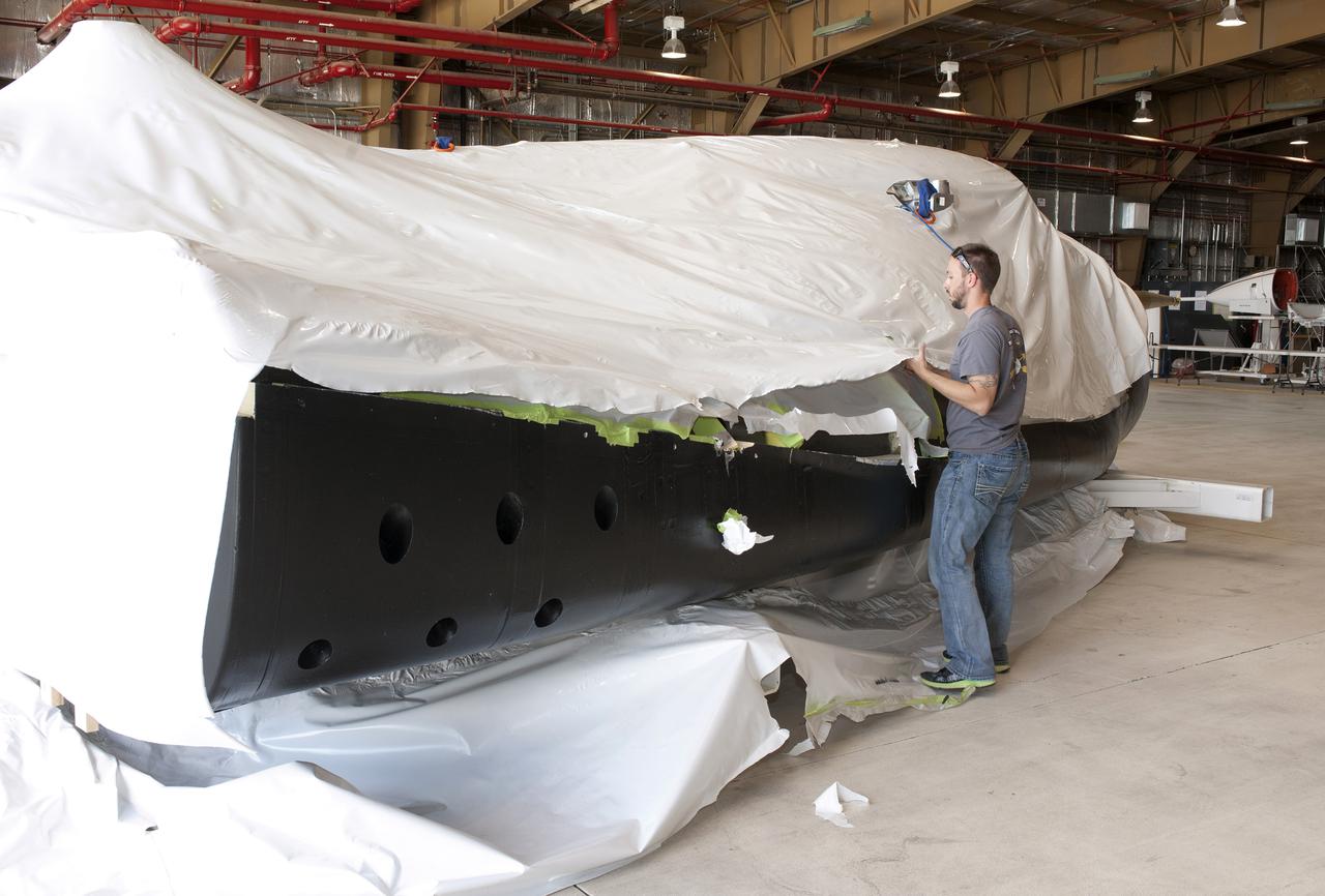 Edwards, Calif. – ED-0144-06 - Plastic wrapping that protected the Sierra Nevada Corporation, or SNC, Dream Chaser flight test vehicle during its transport from Colorado is carefully removed by SNC employee Jason Dixon following the craft's arrival at NASA's Dryden Flight Research Center in southern California. The prototype space access vehicle will undergo ground and approach-and-landing flight tests in the coming months at Dryden as part of NASA's Commercial Crew Program, or CCP, development work. SNC is one of three companies working with CCP during the agency's Commercial Crew Integrated Capability, or CCiCap, initiative, which is intended to lead to the availability of commercial human spaceflight services for government and commercial customers. To learn more about CCP and its industry partners, visit www.nasa.gov_commercialcrew. Image credit: NASA_Tom Tschida