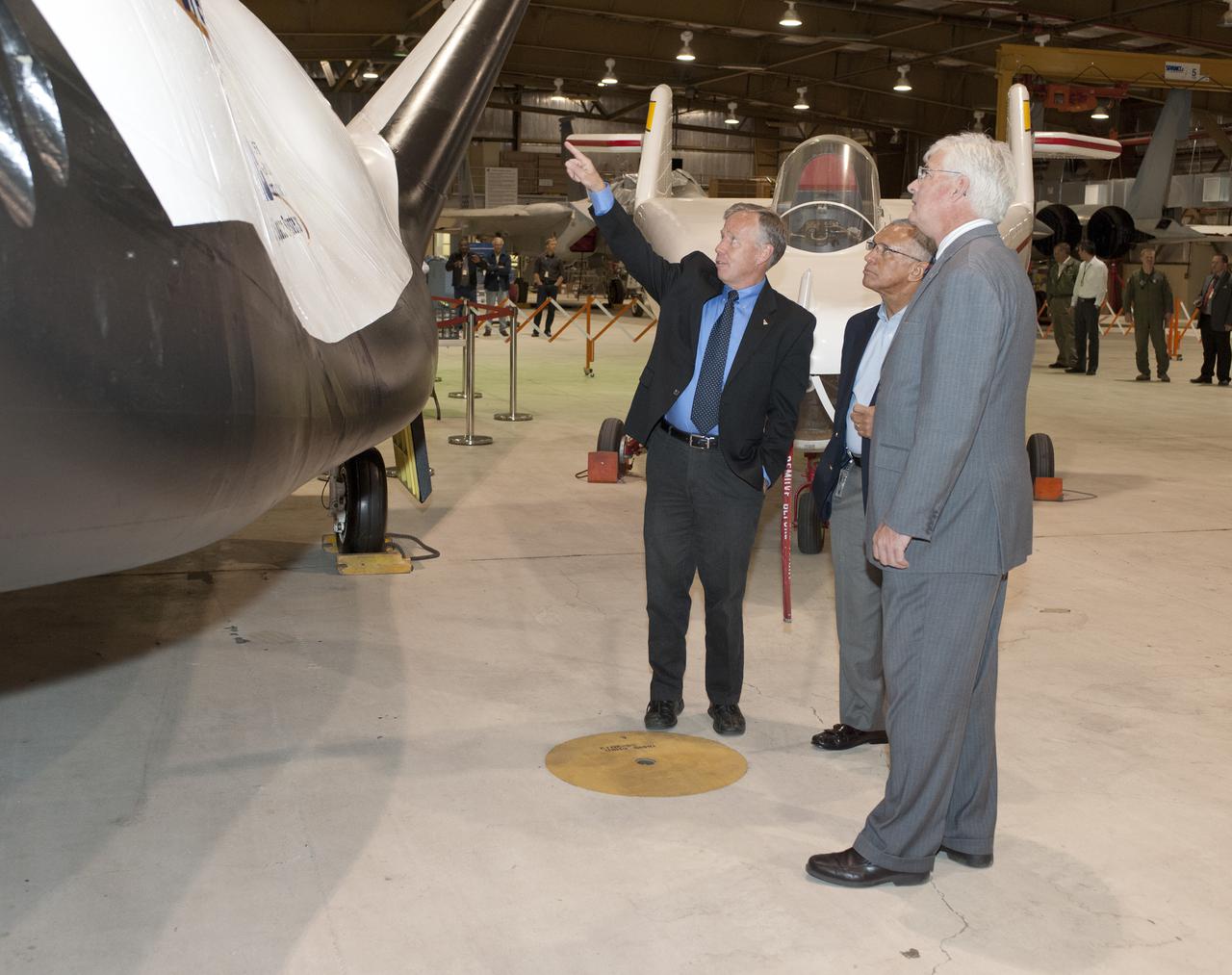 Edwards, Calif. – ED-0155-13 - Steve Lindsey, Sierra Nevada Corporation, or SNC, director of flight operations and former space shuttle astronaut, left, talks to NASA Administrator Charlie Bolden, center, and agency Dryden Flight Research Center Deputy Director Patrick Stoliker about the company's Dream Chaser flight test vehicle. It will undergo ground and approach-and-landing flight tests at Dryden in the coming months as part of NASA's Commercial Crew Program, or CCP, development work.   SNC is one of three companies working with CCP during the agency's Commercial Crew Integrated Capability, or CCiCap, initiative, which is intended to lead to the availability of commercial human spaceflight services for government and commercial customers. To learn more about CCP and its industry partners, visit www.nasa.gov_commercialcrew.    Image credit: NASA_Tom Tschida