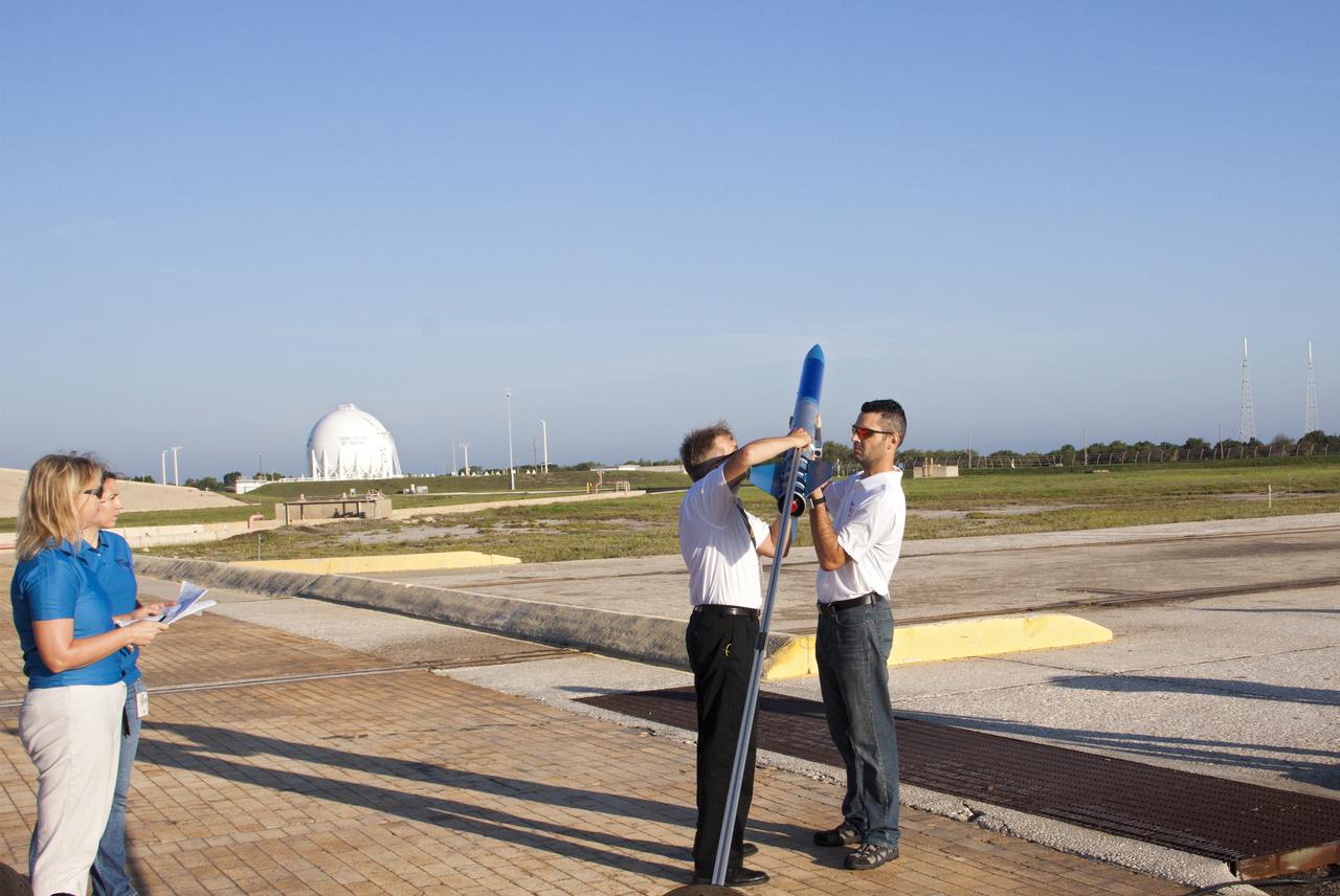 CAPE CANAVERAL, Fla. -- At NASA's Kennedy Space Center in Florida, as Susan Danley of Flight Structures and Kim Simpson of Fluids, Mechanical and Structural Systems look on, Gary Dahlke of Engineering and Technology, left, and Leandro James of Systems Hardware Engineering attach a small rocket prior to its launch stand as part of Rocket University. The goal was to test its systems and to verify that it performed as designed. As part of Rocket University, the engineers are given an opportunity to work a fast-track project to develop skills in developing spacecraft systems of the future. As NASA plans for future spaceflight programs to low-Earth orbit and beyond, teams of engineers at Kennedy are gaining experience in designing and flying launch vehicle systems on a small scale. Four teams of five to eight members from Kennedy are designing rockets complete with avionics and recovery systems. Launch operations require coordination with federal agencies, just as they would with rockets launched in support of a NASA mission. Photo credit: NASA_Jim Grossmann