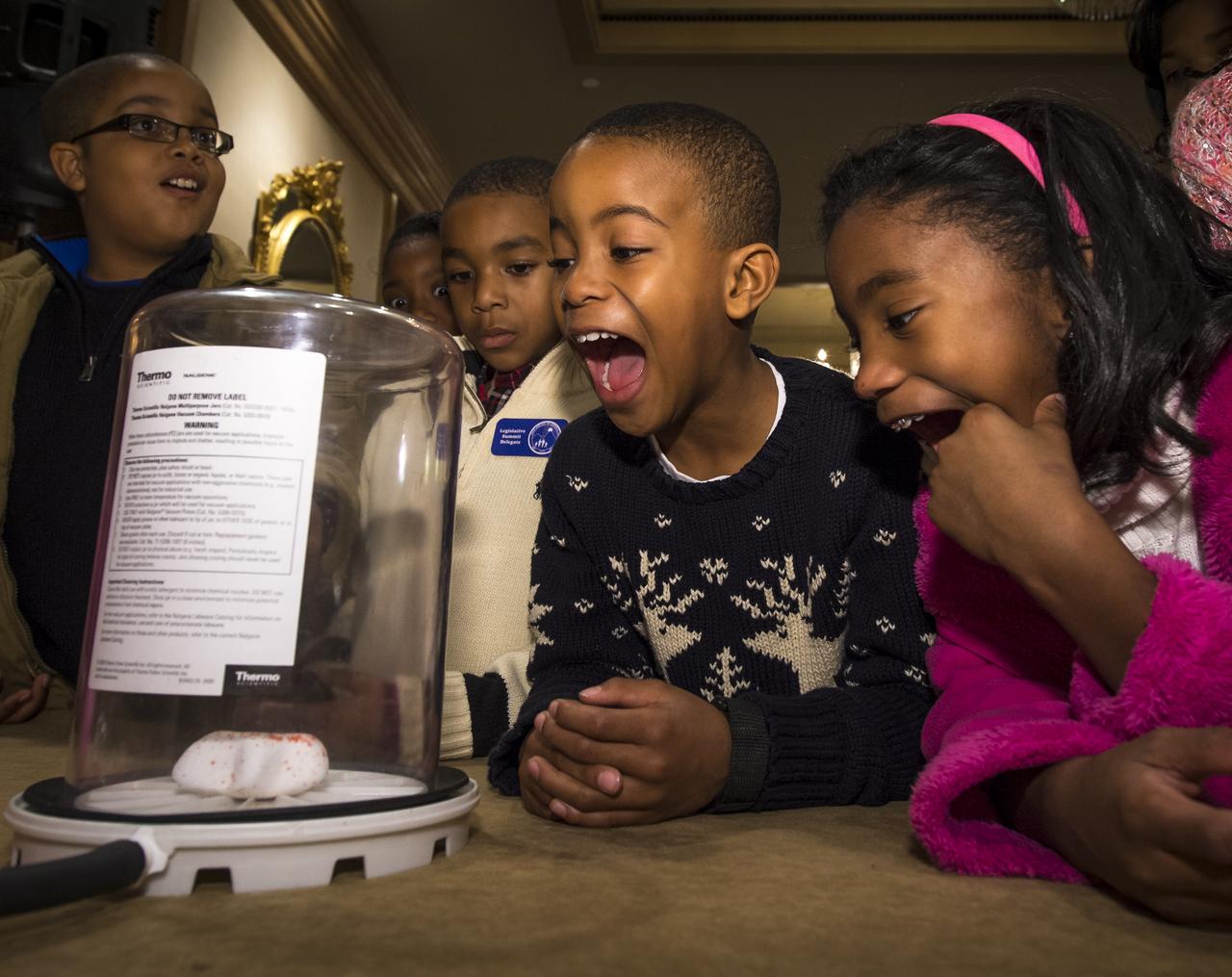 School children react to food shrinking in a vacuum chamber during an Science, Technology, Engineering, and Math (STEM) education event held at the Ritz-Carlton Hotel in Arlington, VA on Saturday, Jan. 19, 2013.  Students were able to meet with Astronaut Melvin, conduct experiments, build their own space jab, and touch a mockup space suit.  Photo Credit: (NASA/Bill Ingalls)