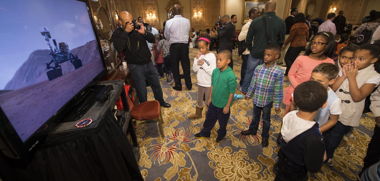 School children watch a TV program showing how the Mars rover Curiosity landed on Mars during an Science, Technology, Engineering, and Math (STEM) education event held at the Ritz-Carlton Hotel in Arlington, VA on Saturday, Jan. 19, 2013.  Students were able to meet with Astronaut Melvin, conduct experiments, build their own space jab, and touch a mockup space suit.  Photo Credit: (NASA/Bill Ingalls)