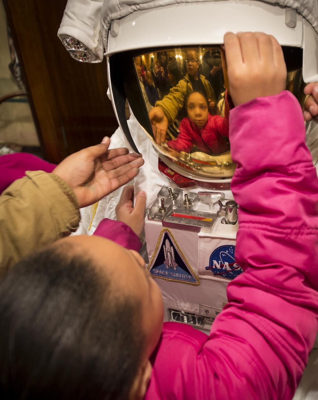 School children are given a hands-on experience with a mock spacesuit during a Science, Technology, Engineering, and Math (STEM) education event held at the Ritz-Carlton Hotel in Arlington, VA on Saturday, Jan. 19, 2013.  Students were able to meet with Astronaut Leland Melvin, conduct experiments, build their own space jab, and touch a mockup space suit.  Photo Credit: (NASA/Bill Ingalls)