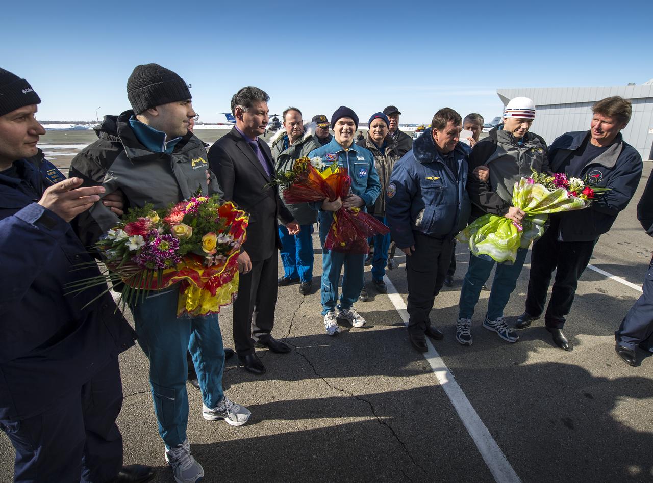 Expedition 34 Russian Flight Engineer Evgeny Tarelkin, left with flowers, Commander Kevin Ford of NASA, center with flowers, and Russian Soyuz Commander Oleg Novitskiy are greeted at the Kustanay Airport a few hours after they landed near the town of Arkalyk, Kazakhstan on Saturday, March 16, 2013. Ford, Novitskiy, and Tarelkin are returning from 142 days onboard the International Space Station where they served as members of the Expedition 33 and 34 crews. Photo Credit: (NASA/Bill Ingalls)