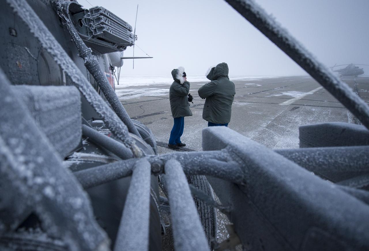 NASA Astronauts Eric Boe, left, and Bob Behnken are seen making contact with other team members outside a Search and Rescue helicopter that was grounded by low visibility at the Arkalyk Airport in Kazakhstan on Saturday, March 16, 2013. The Soyuz TMA-06M spacecraft landed with Expedition 34 Commander Kevin Ford of NASA, Russian Soyuz Commander Oleg Novitskiy and Russian Flight Engineer Evgeny Tarelkin near the town of Arkalyk, Kazakhstan on Saturday, March 16, 2013. Ford, Novitskiy, and Tarelkin returned from 142 days onboard the International Space Station where they served as members of the Expedition 33 and 34 crews. Photo Credit: (NASA/Bill Ingalls)