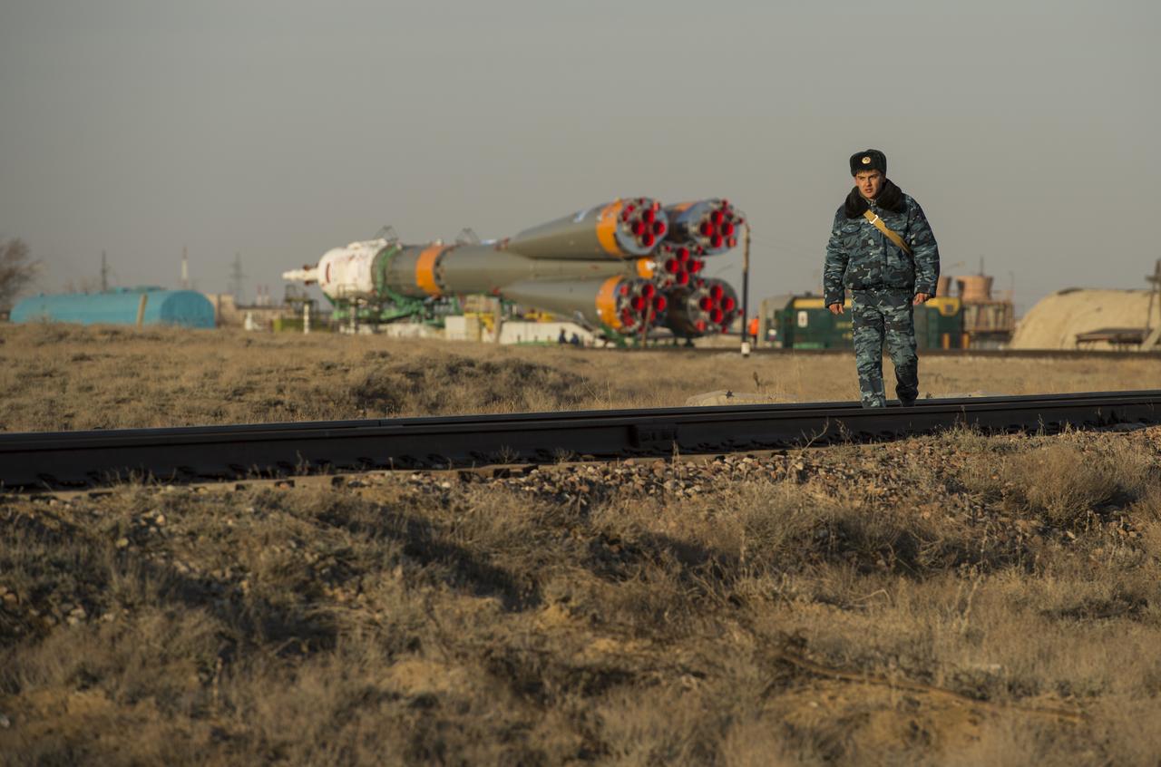 A Russian security guard is seen walking along the train tracks with the Soyuz rocket in the background on Tuesday, March 26, 2013, at the Baikonur Cosmodrome in Kazakhstan. Launch of the Soyuz rocket is scheduled for March 29 and will send Expedition 35 Soyuz Commander Pavel Vinogradov, and Flight Engineers Chris Cassidy of NASA and Alexander Misurkin of Russia on a five and a half-month mission aboard the International Space Station. Photo Credit: (NASA/Carla Cioffi)